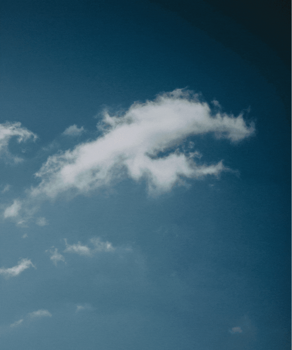 A sky with a few small white clouds scattered across a blue background.
