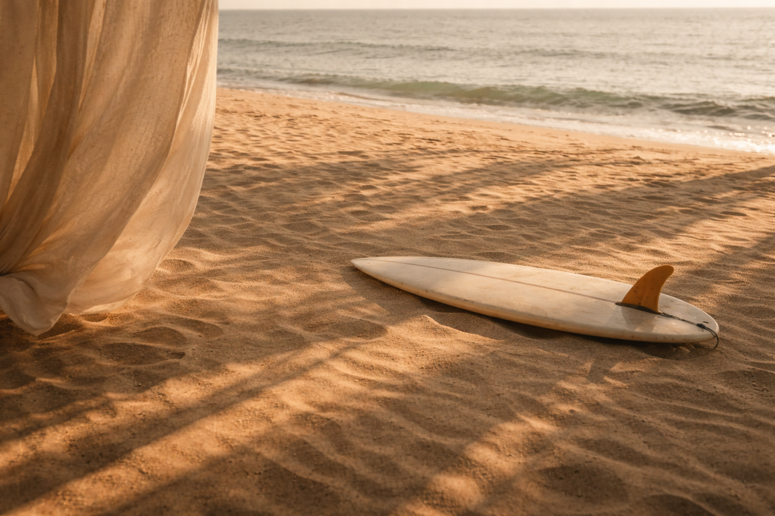 A surfboard with a yellow fin lying on the sandy beach near the ocean, with shading from a tent or beach umbrella on the left side.