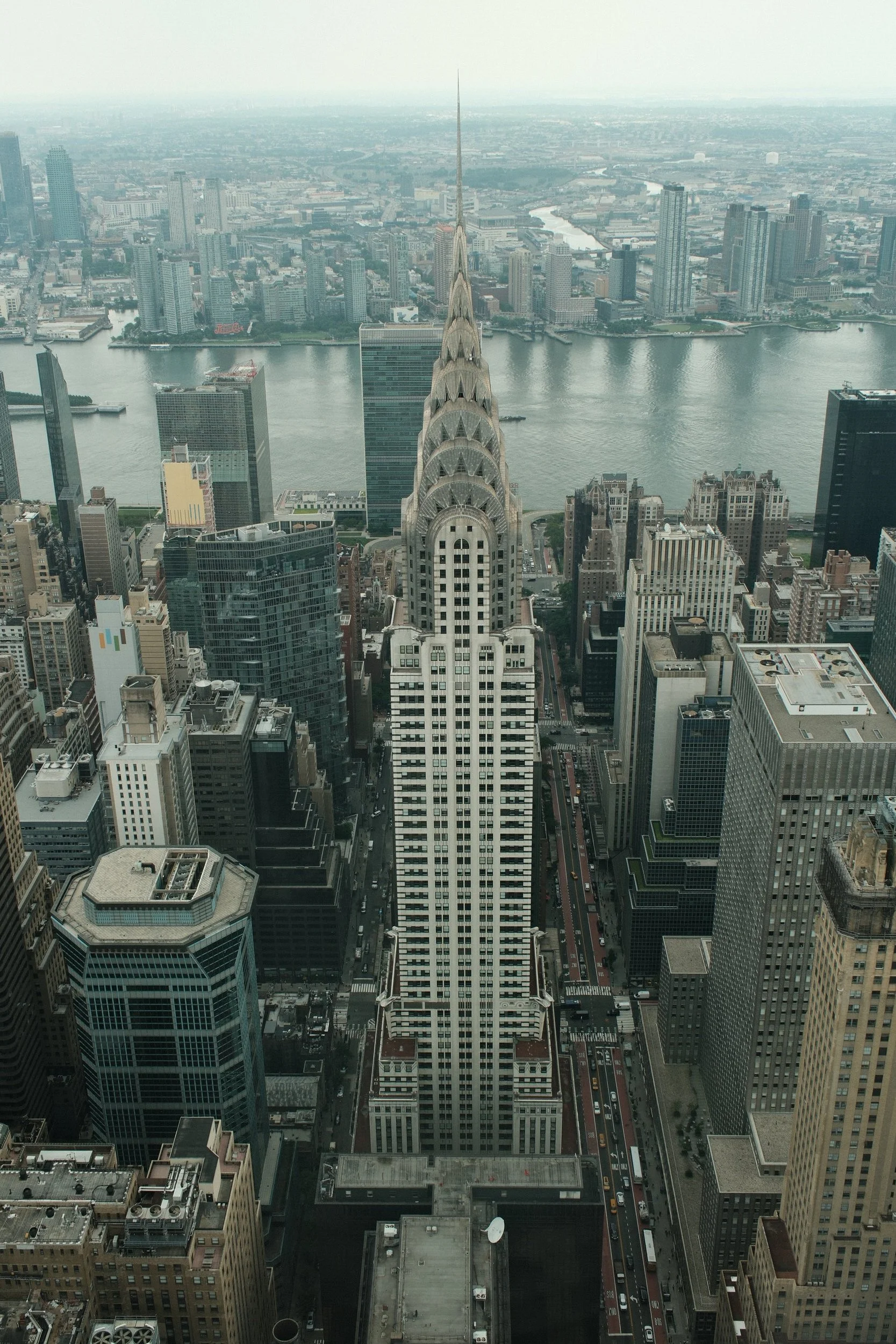 Aerial view of Manhattan, New York City, showing the Chrysler Building in the foreground and the East River with city skyline in the background.