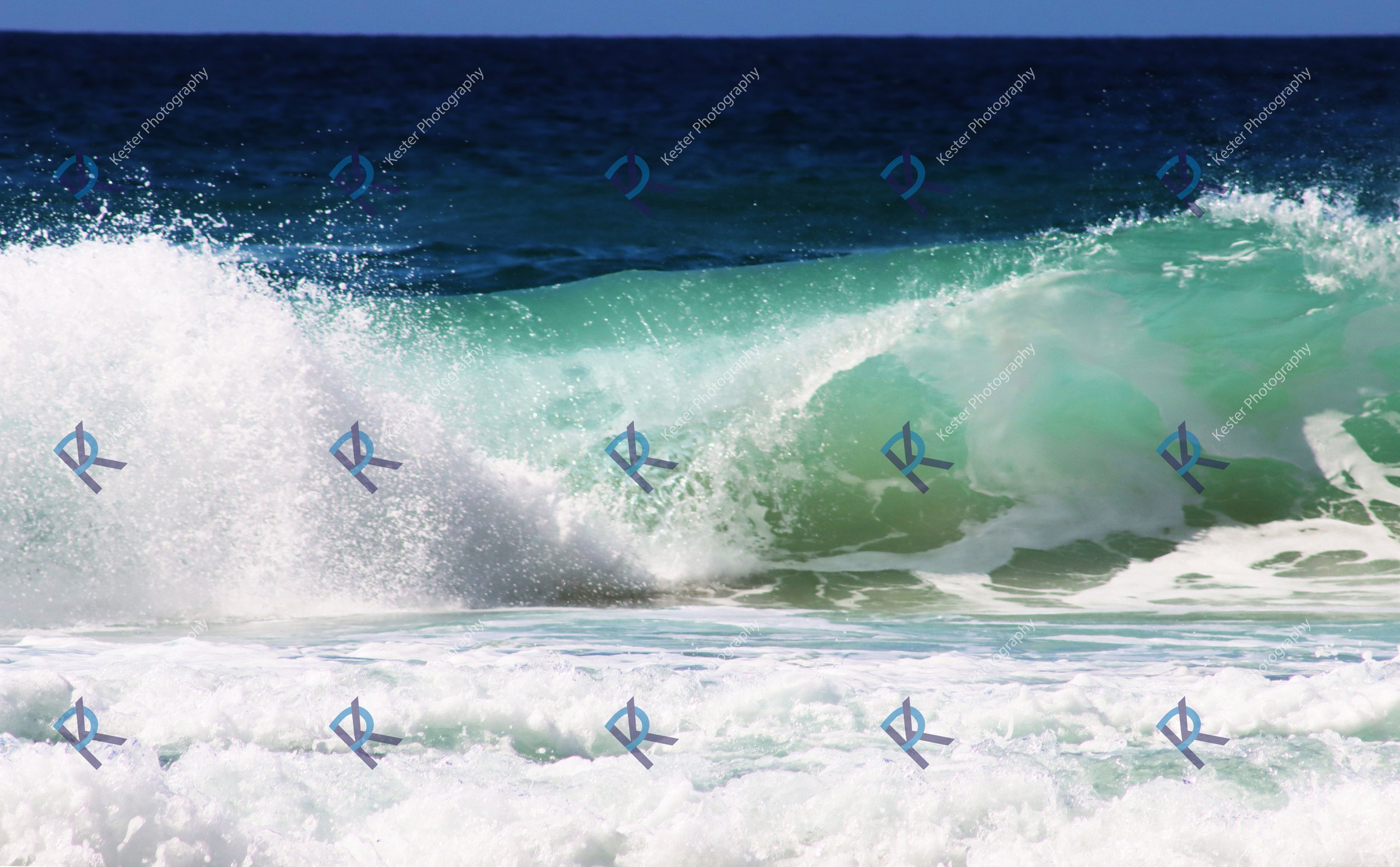 Ocean waves crashing with white foam and a green wave curling near the shore.