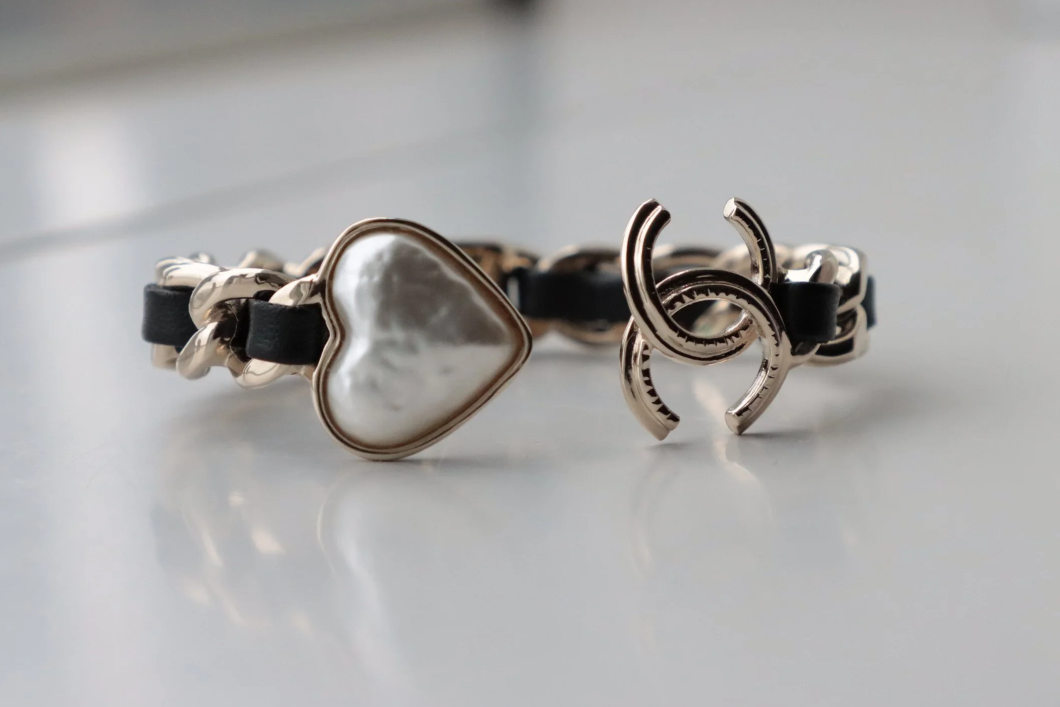 Fashion bracelet with black leather bands and mother of pearl on a white surface.