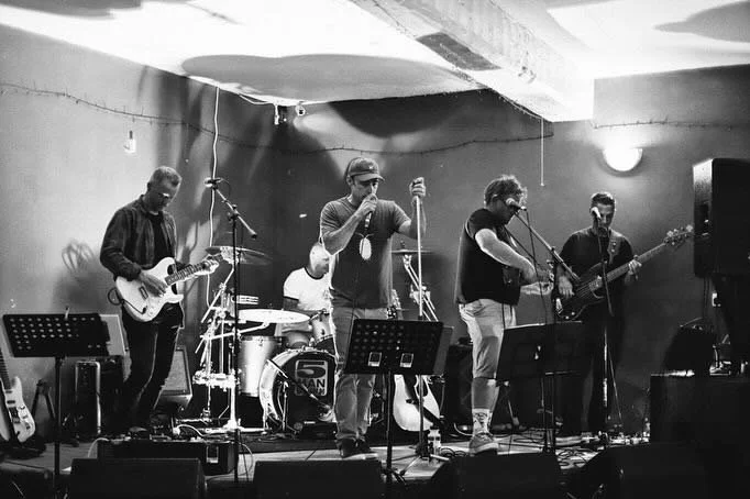 5 Man Down performing on stage with guitars, drums, and microphones in an indoor venue.