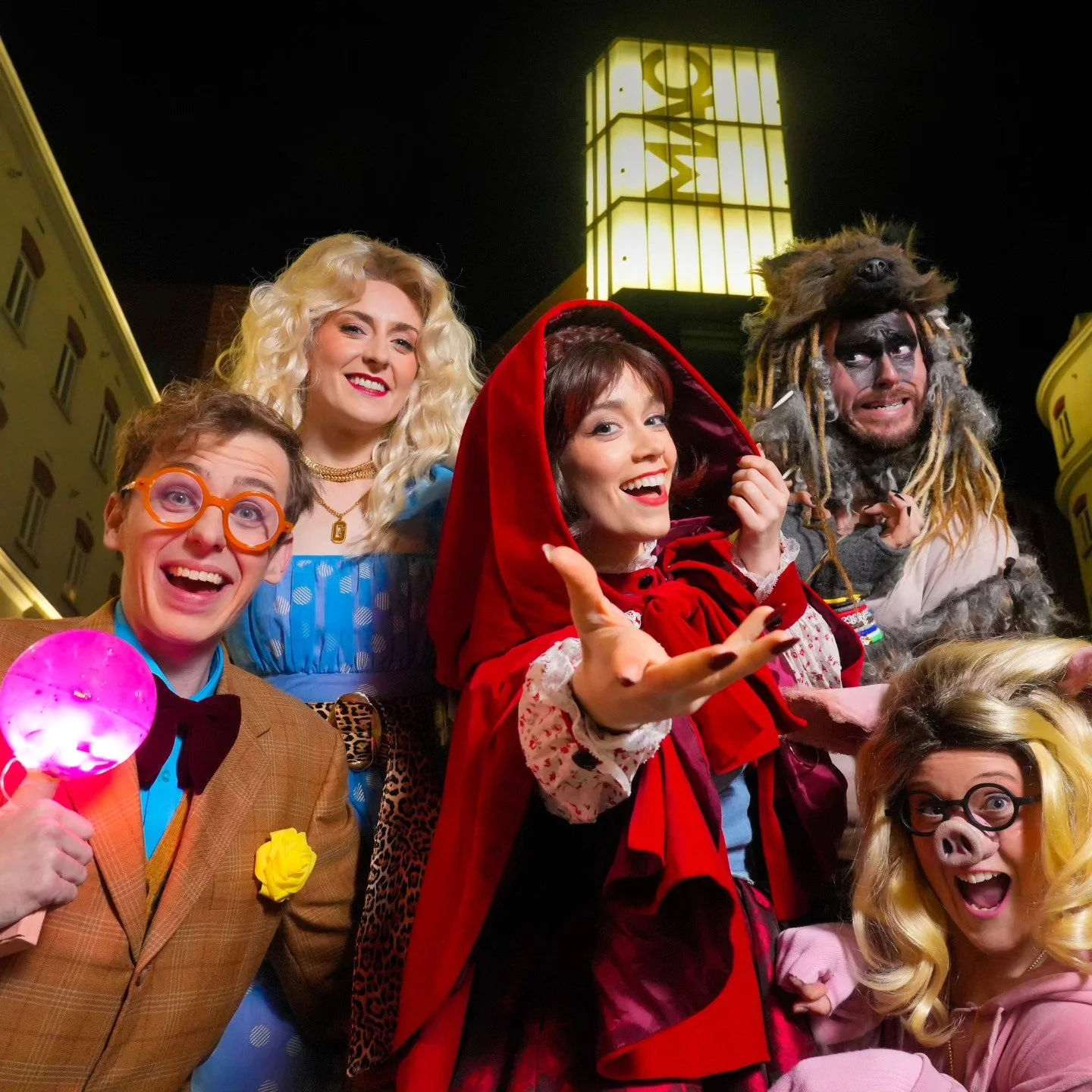 Group of people in costumes smiling and having fun outdoors at night.