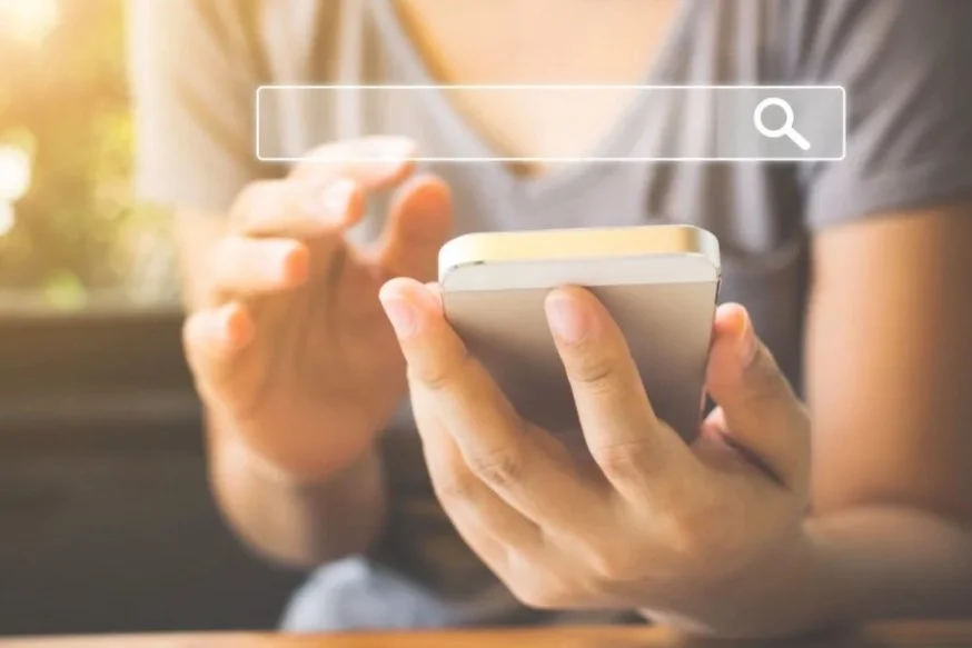 Person holding a smartphone with a search bar overlay on the screen