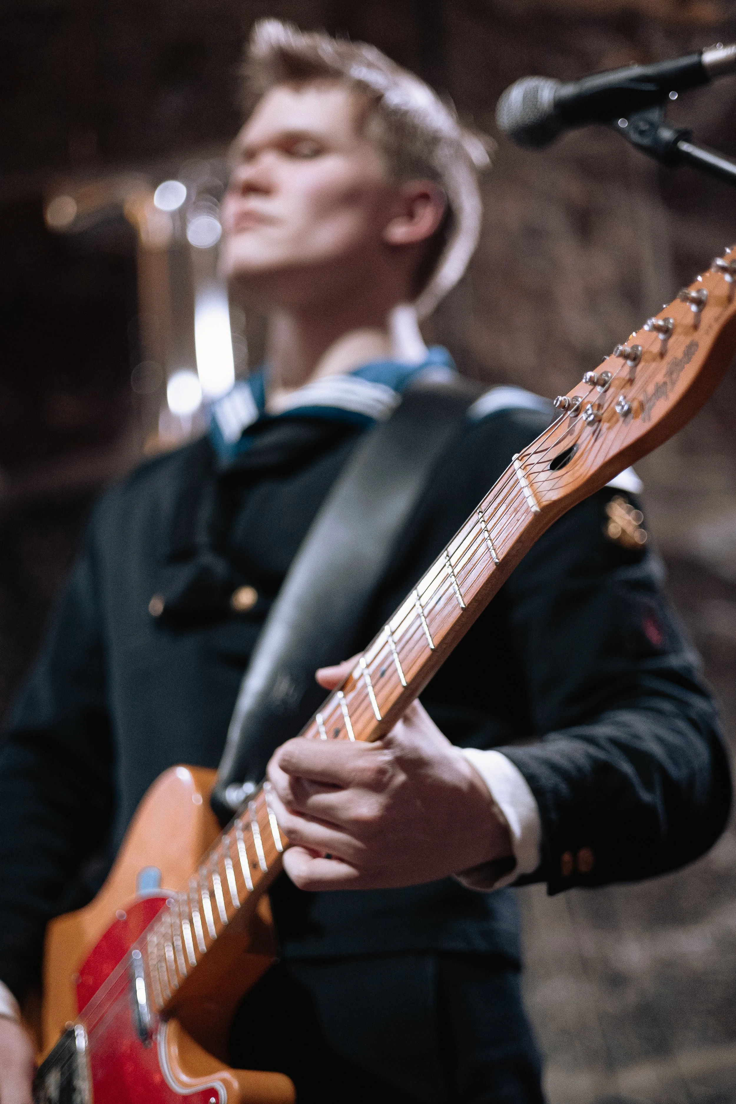A person playing an electric guitar in a dimly lit environment.
