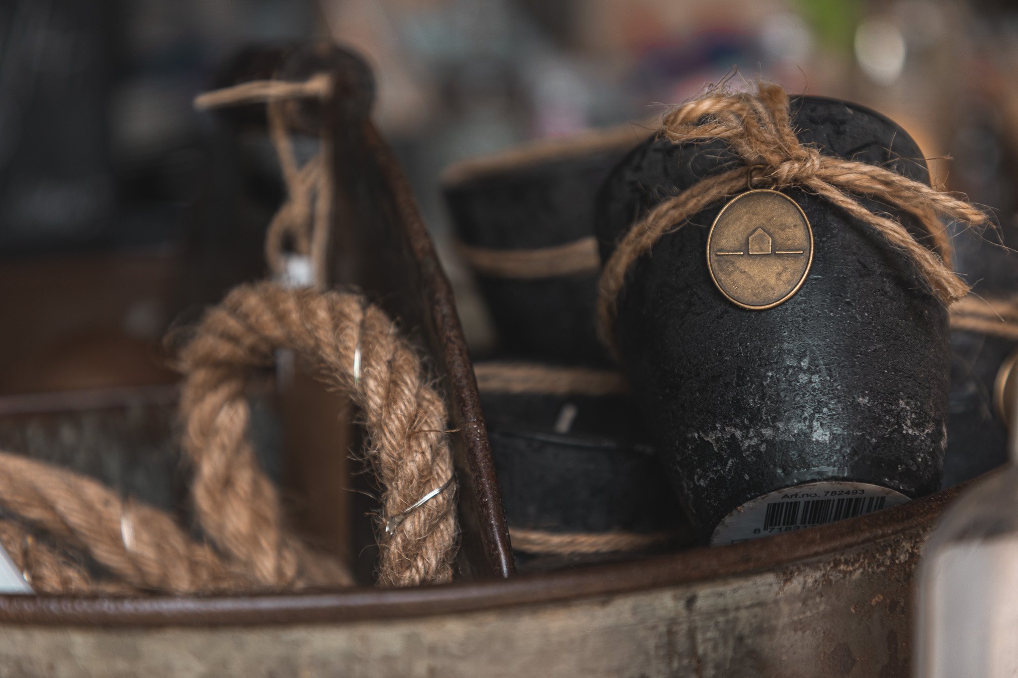 Close-up of black, rustic boots tied with jute string, with a brass country store tag, inside a wooden container with other vintage items.