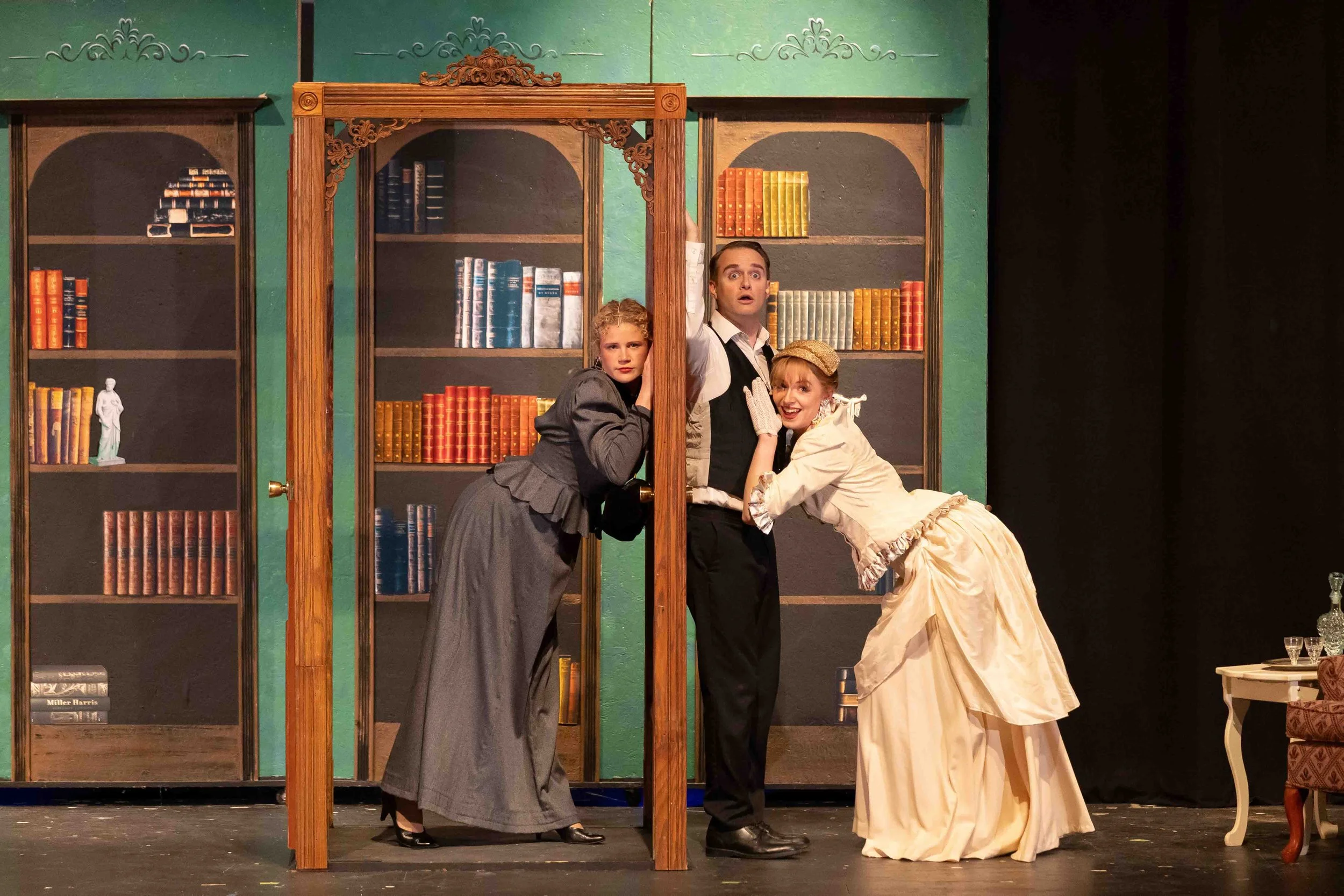Scene from A Gentleman's Guide To Love And Murder with Sibella and Phoebe both leaning against Monty.