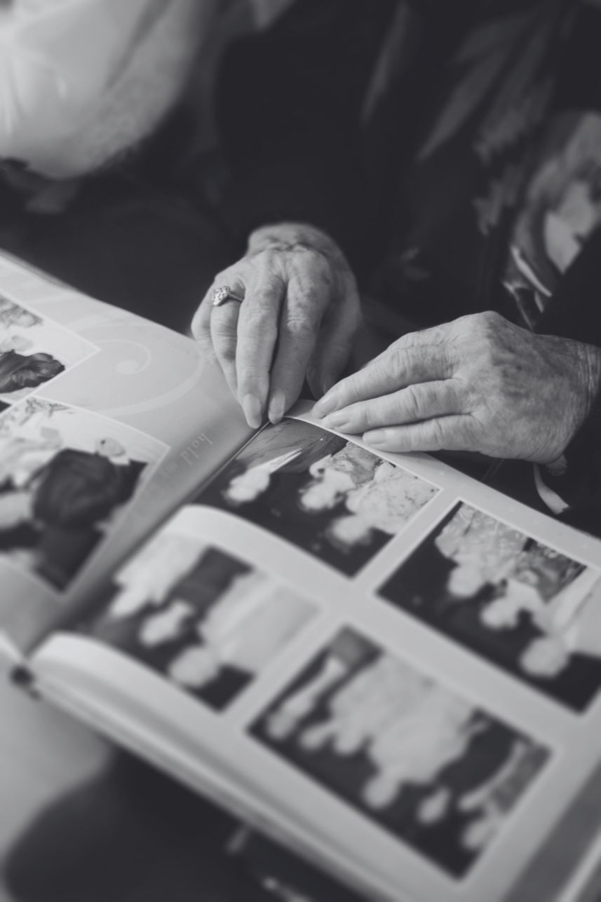 Close-up of elderly person flipping through a photo album, viewing various black-and-white photographs.