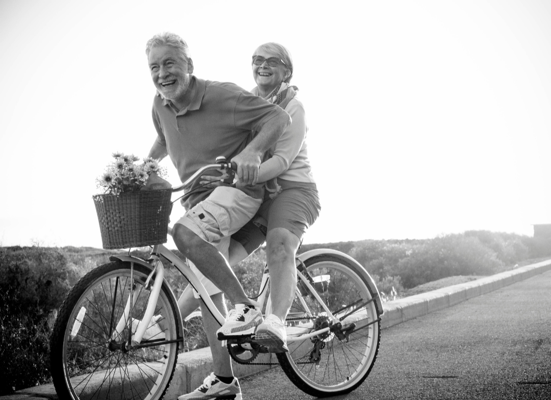 elderly couple laughing together while cycling and creating memories