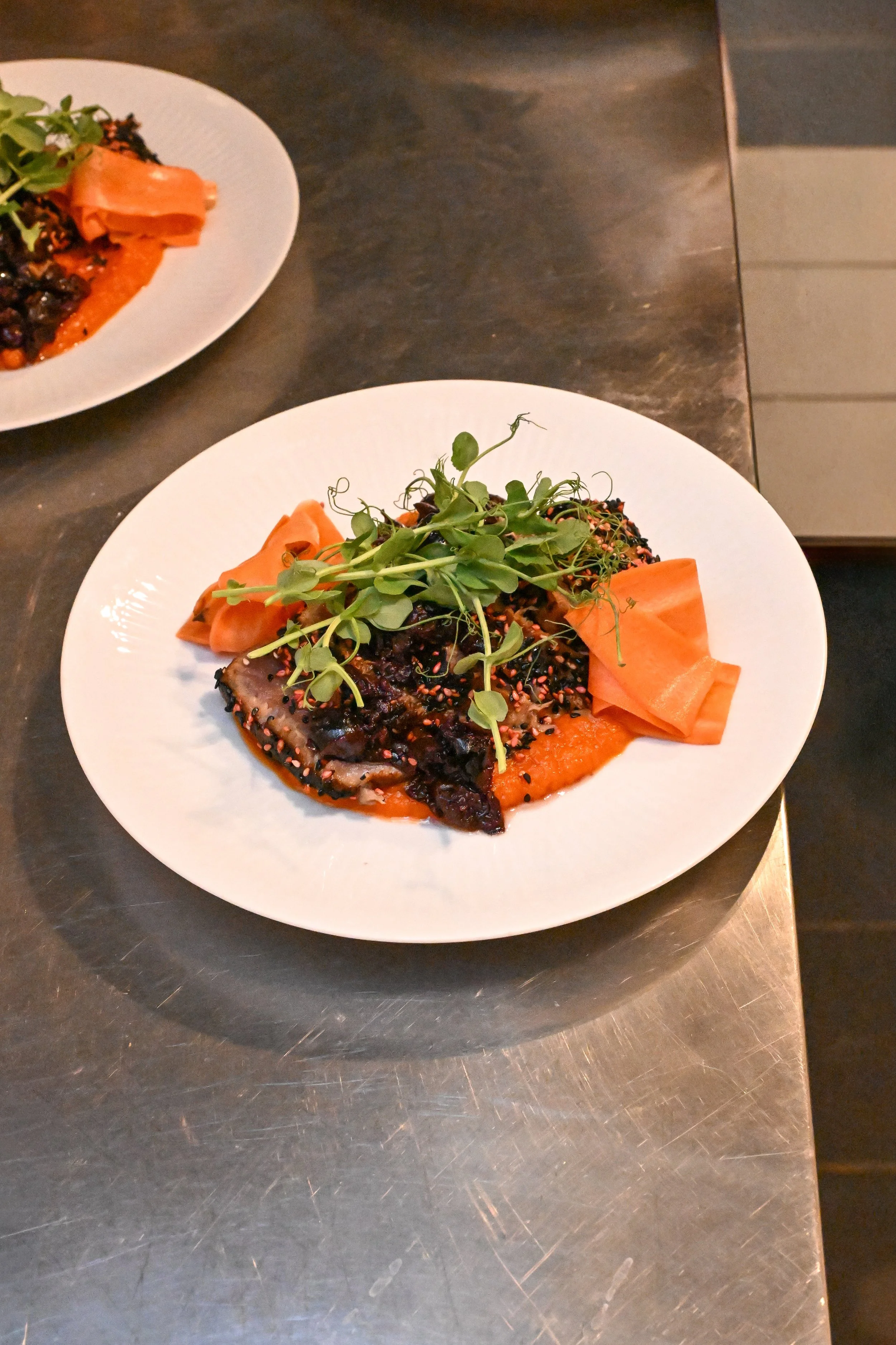 Assiette originale avec une crème de carottes fumées, un tataki de sériole au sésame grillé et des carottes fermentées. Un dîner sain et original dans un bistrot méditerranéen.