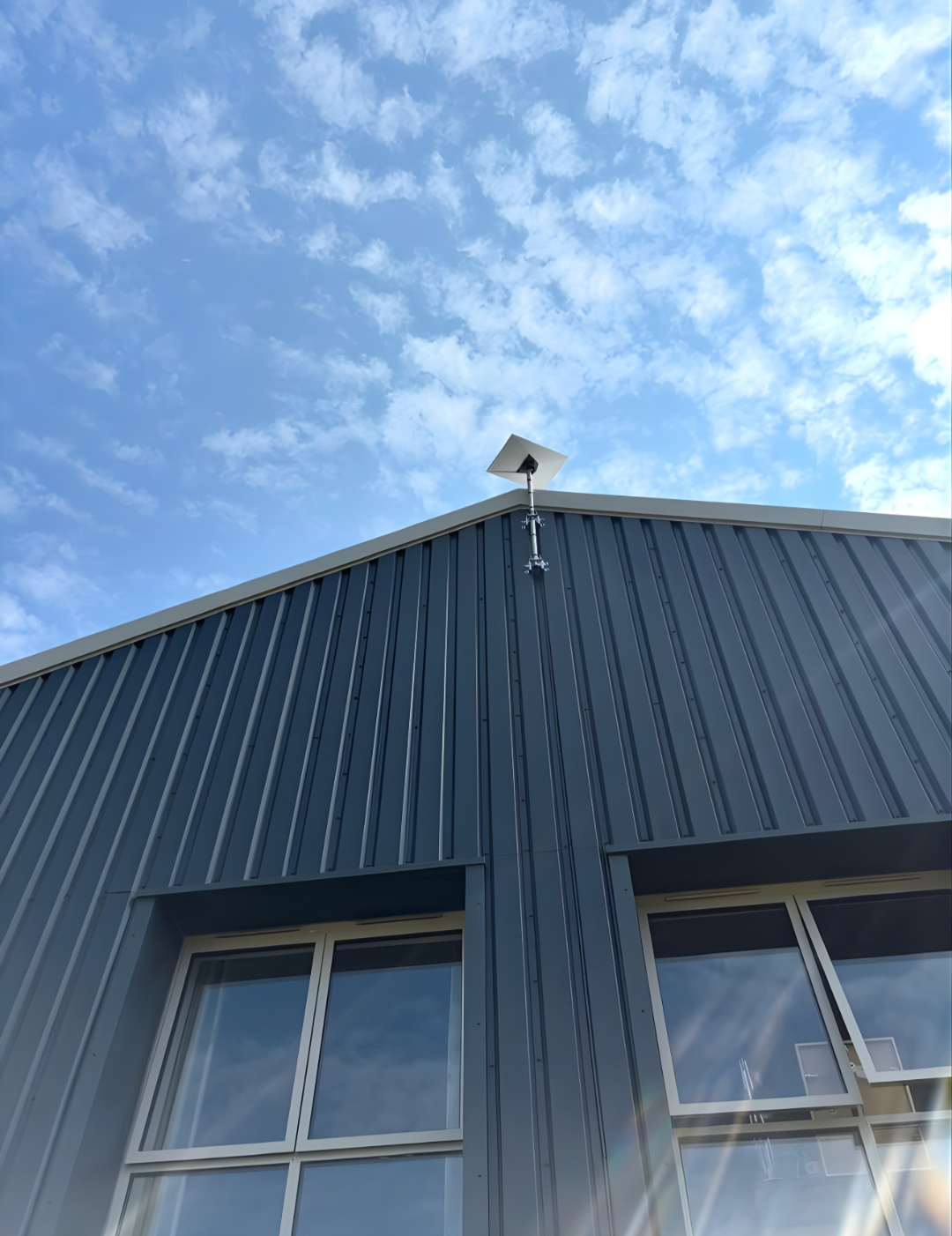 The image shows Starlink internet installed on a metal building against a blue sky