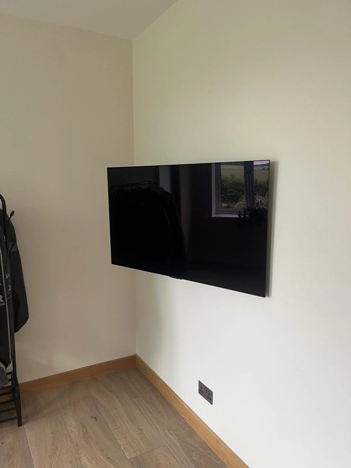 Flat-screen television mounted on a white wall in a corner of a room.