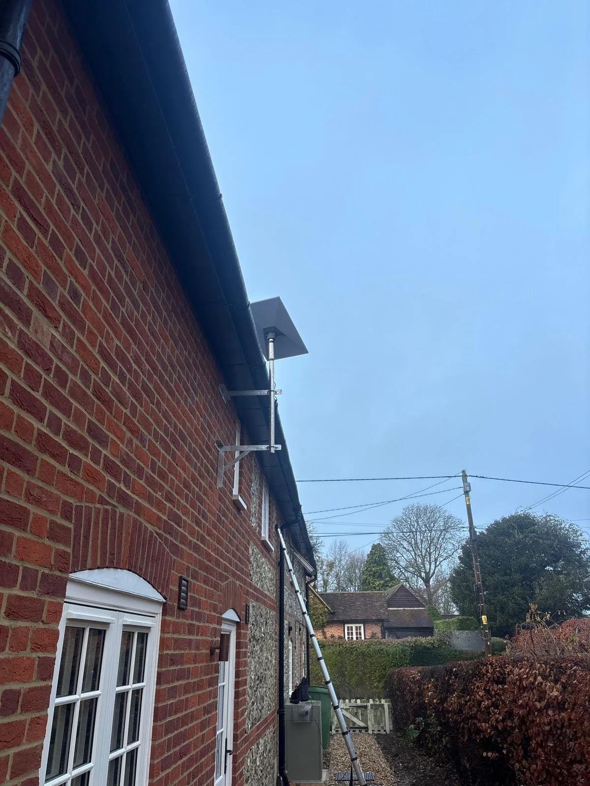 Exterior of a brick house with Starlink satellite internet installed on brackets pointing towards the sky with no obstruction 