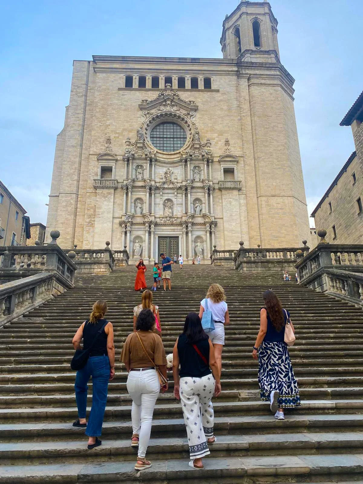Tourists ascending the steps of a historic church in Italy, with ornate architectural details.
