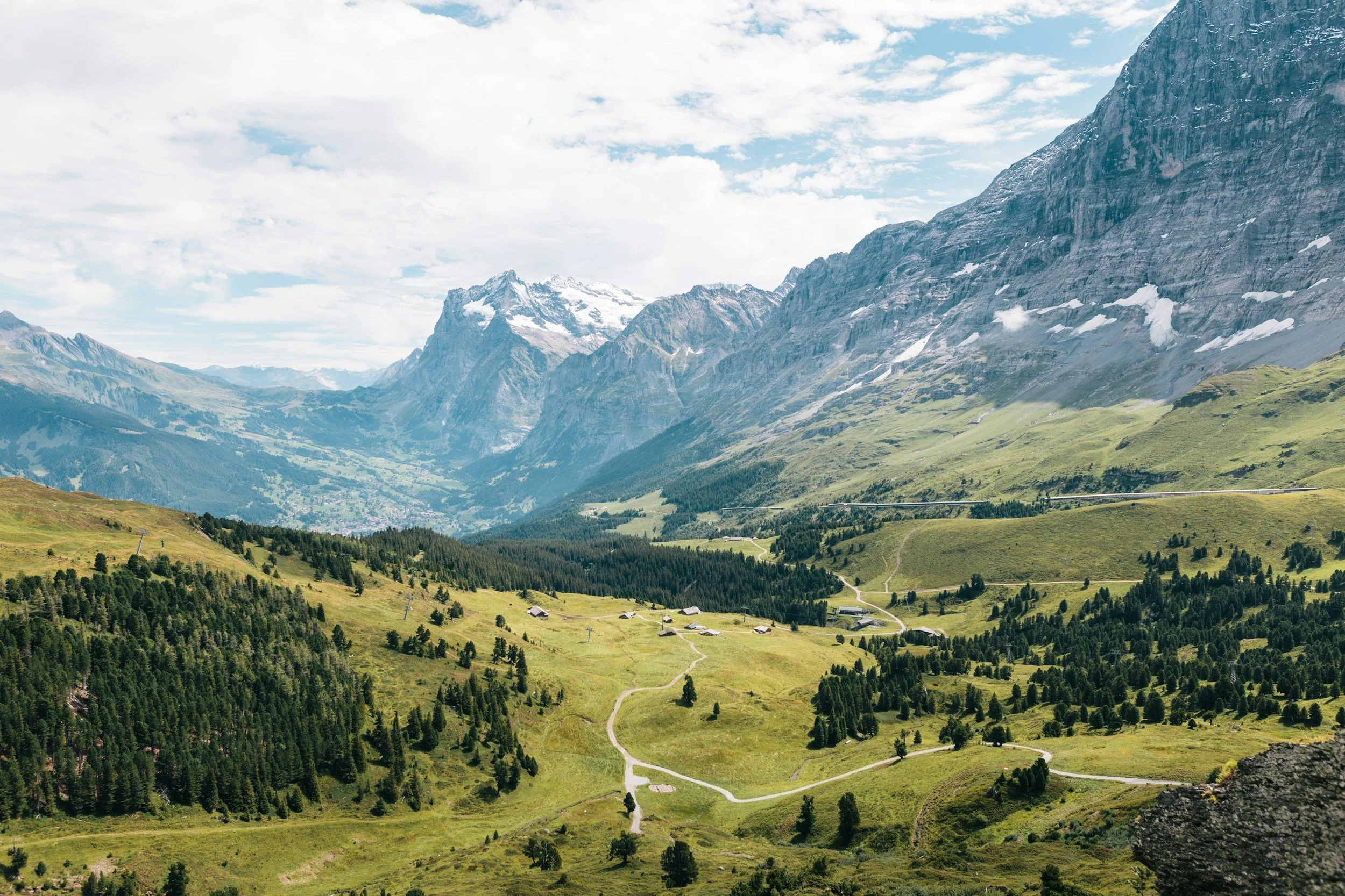 A green Alpine valley beneath rocky mountain peaks.