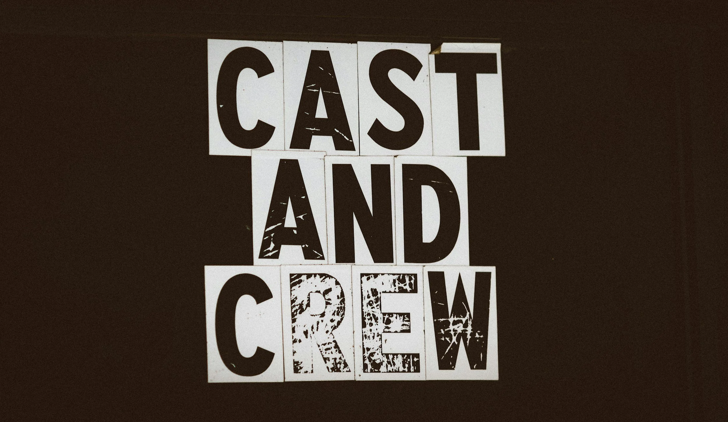 Arrangement of letter blocks spelling out "Cast and Crew" on a black background.