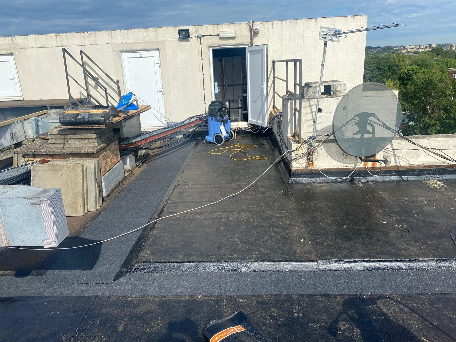 Rooftop with HVAC equipment, a satellite dish, an antenna, and a door leading inside a building.