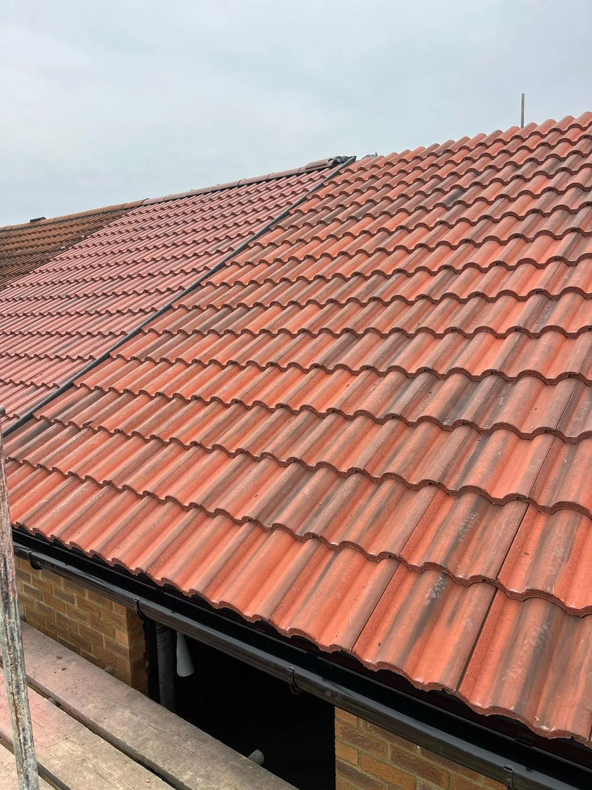 A tiled roof with reddish-orange tiles, partially under renovation with scaffolding visible at the bottom.