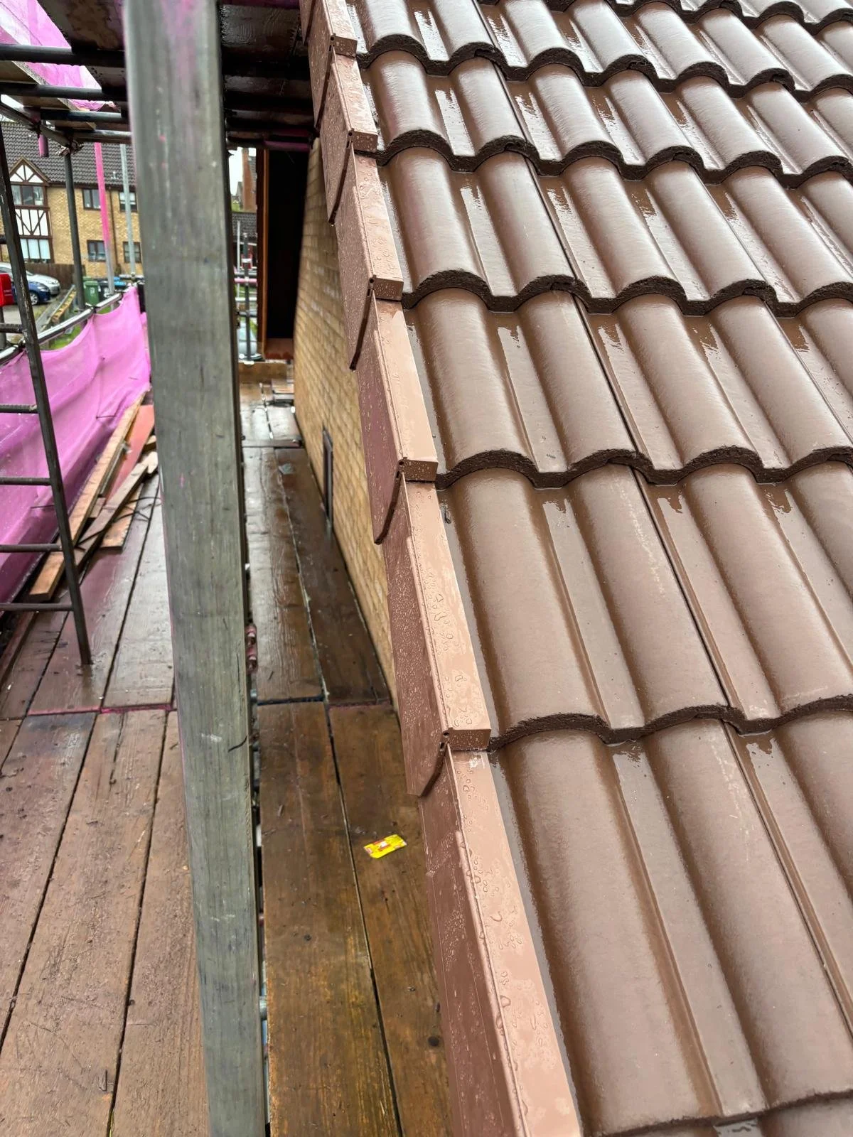 Hot crack unit being installed on a roof with brown curved tiles, scaffolding, and wooden platform.
