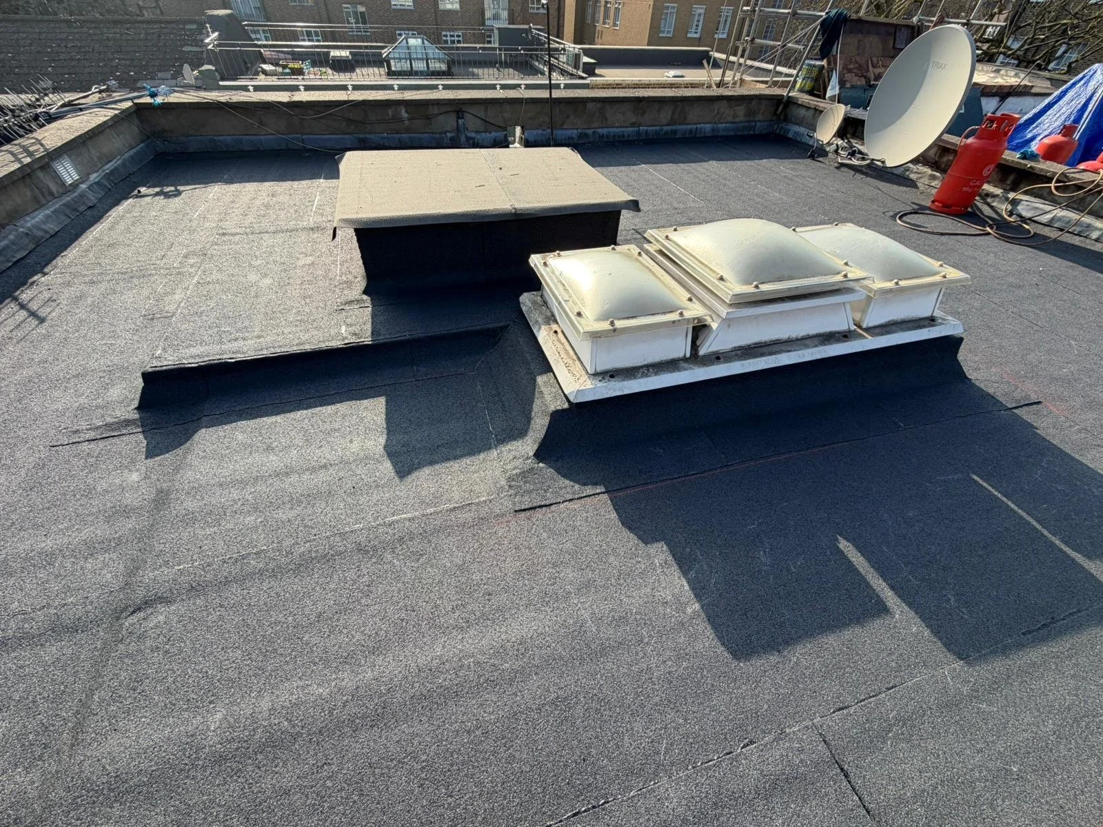 Roof repair Maida Vale with skylights, satellite dish, propane tank, and equipment.