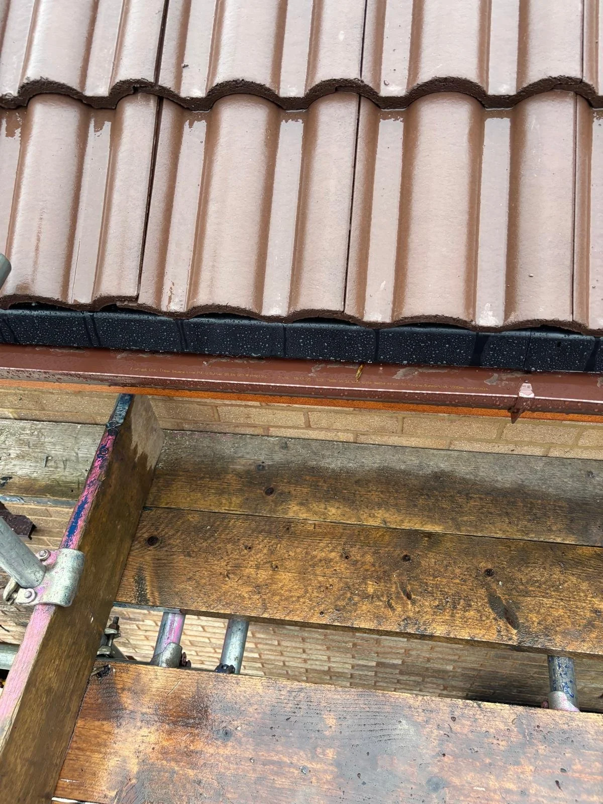 Close-up of roof shingles and wooden scaffolding on a building under construction or repair.