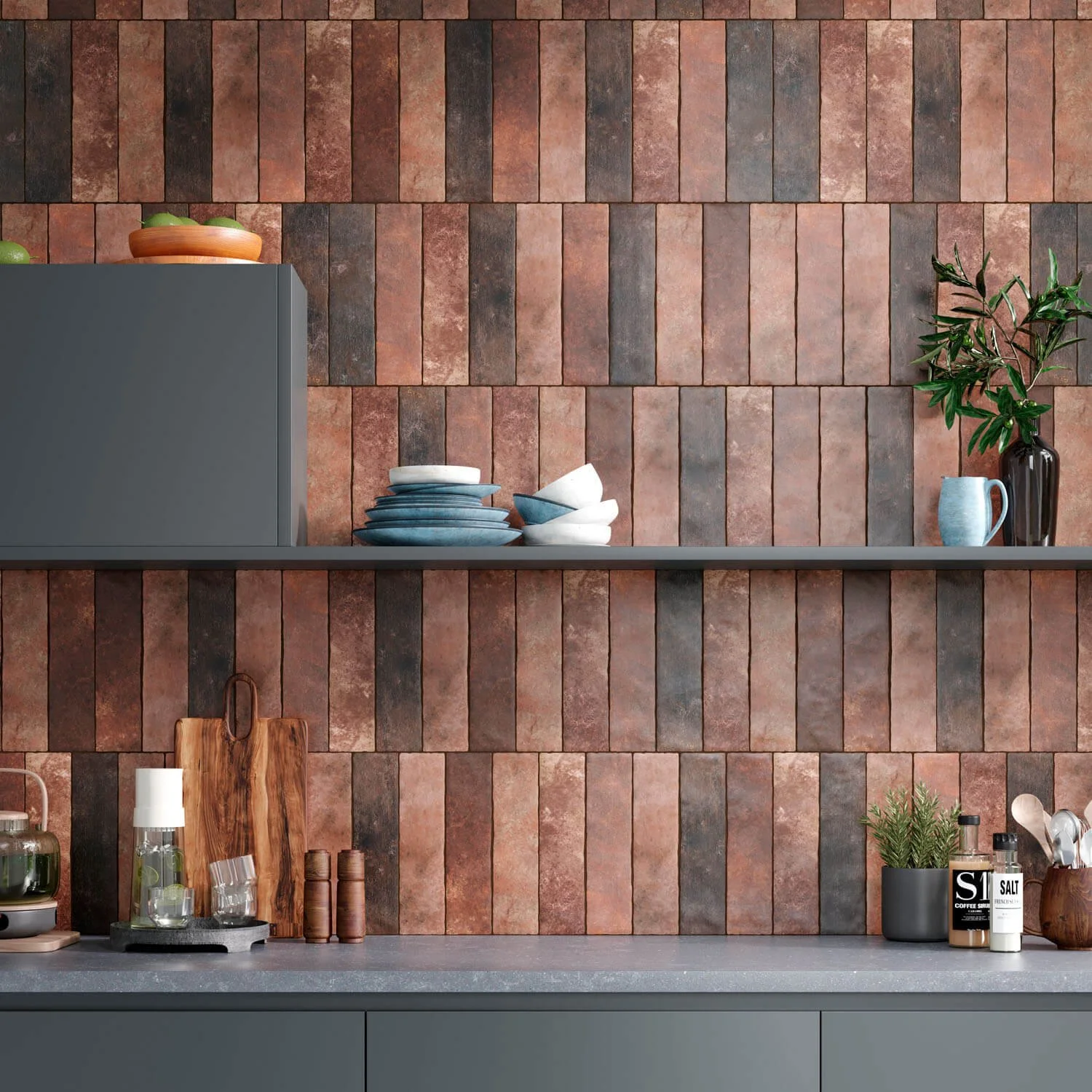 Coupes de verres, planches à découper, piment, sel, huile, assiettes, vaisselle, plantes et ustensiles de cuisine sur un plan de travail dans une cuisine moderne avec mur en briques.
