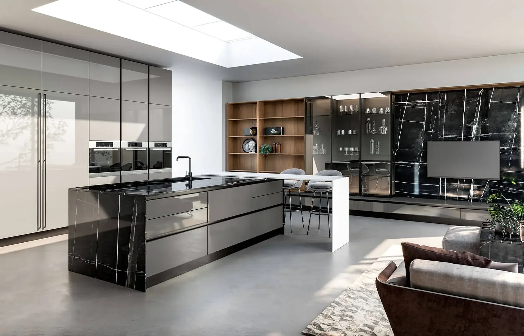 Cuisine moderne avec îlot noir en marbre, armoires grises, étagères en bois, télévision murale, et coin salon en arrière-plan.