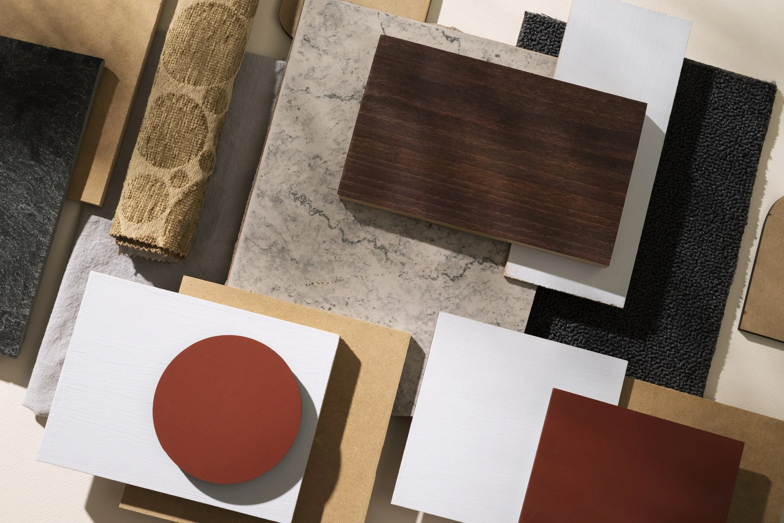 Différents matériaux et échantillons de textures, incluant des pièces en bois, pierre, tissu et plastique, disposés sur une surface pour une sélection de design intérieur.