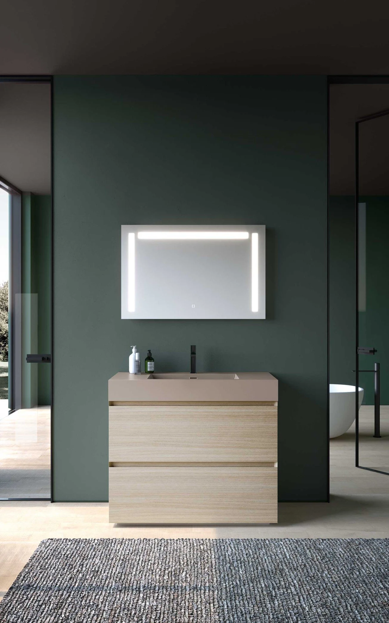 Un lavabo moderne en bois clair avec un miroir éclairé au-dessus, dans une salle de bain au mur vert foncé.