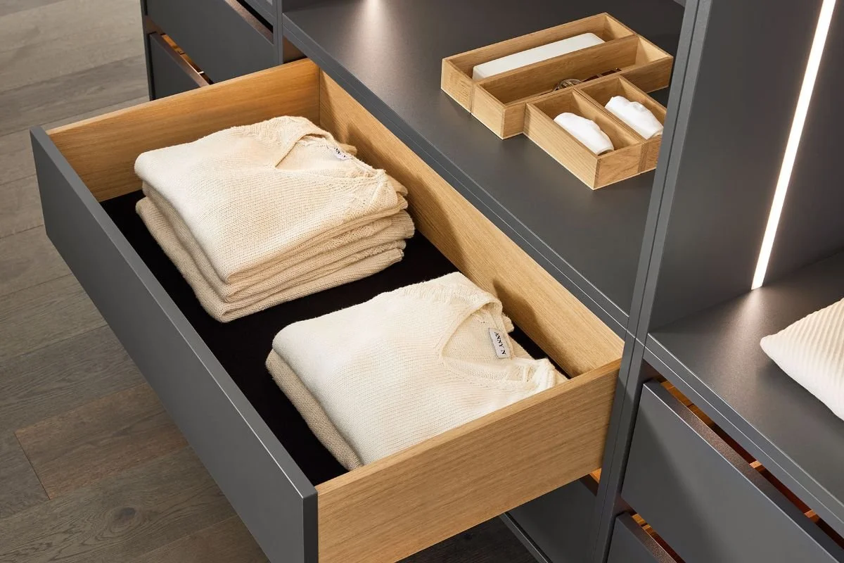 Cinq pulls de vêtements en laine beige rangés dans un tiroir ouvert