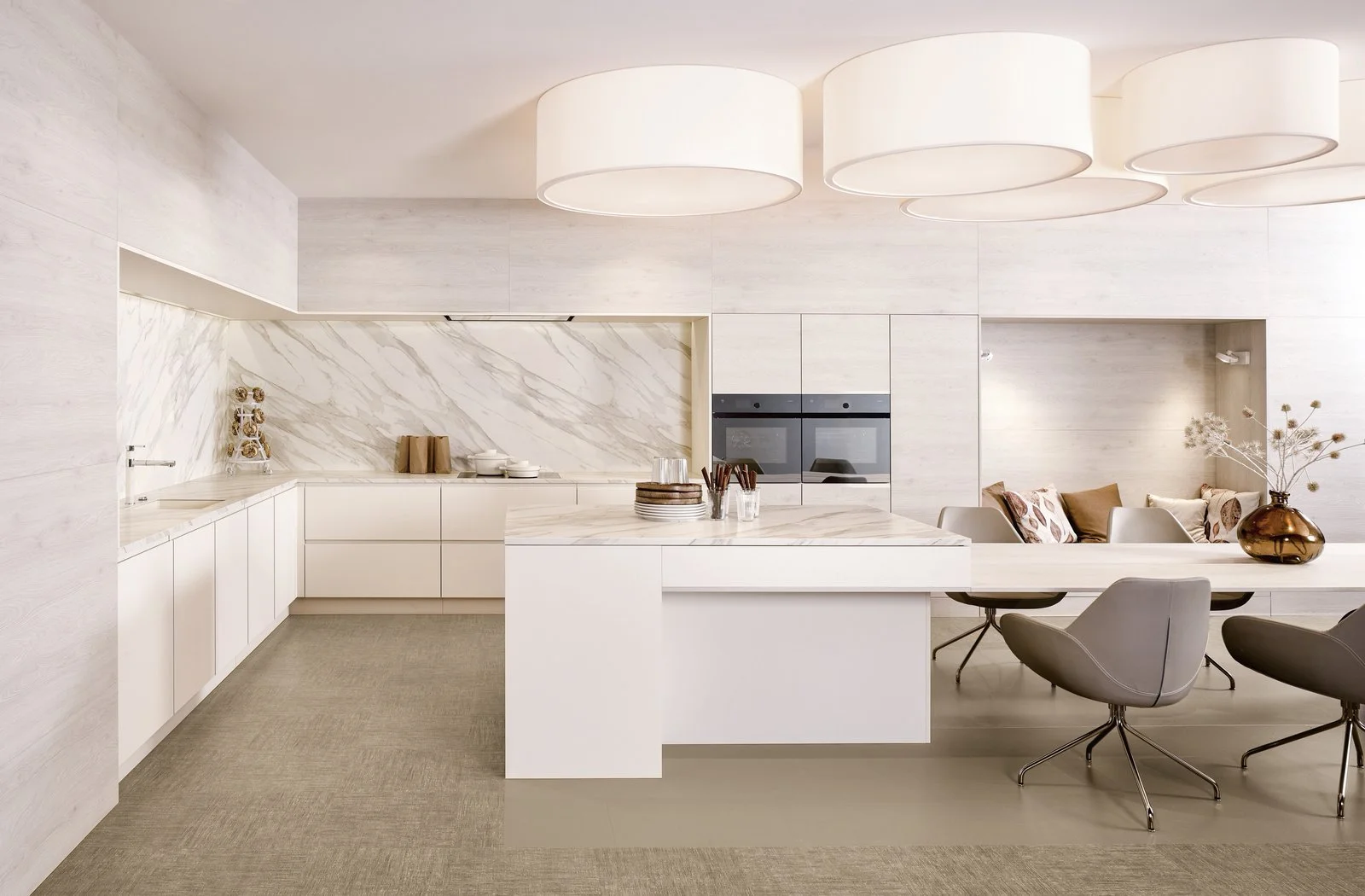 Cuisine sur-mesure AFURNI, agencement minimaliste blanc : table centrale, chaises modernes, banc avec coussins, vase en havane et plante sèche.