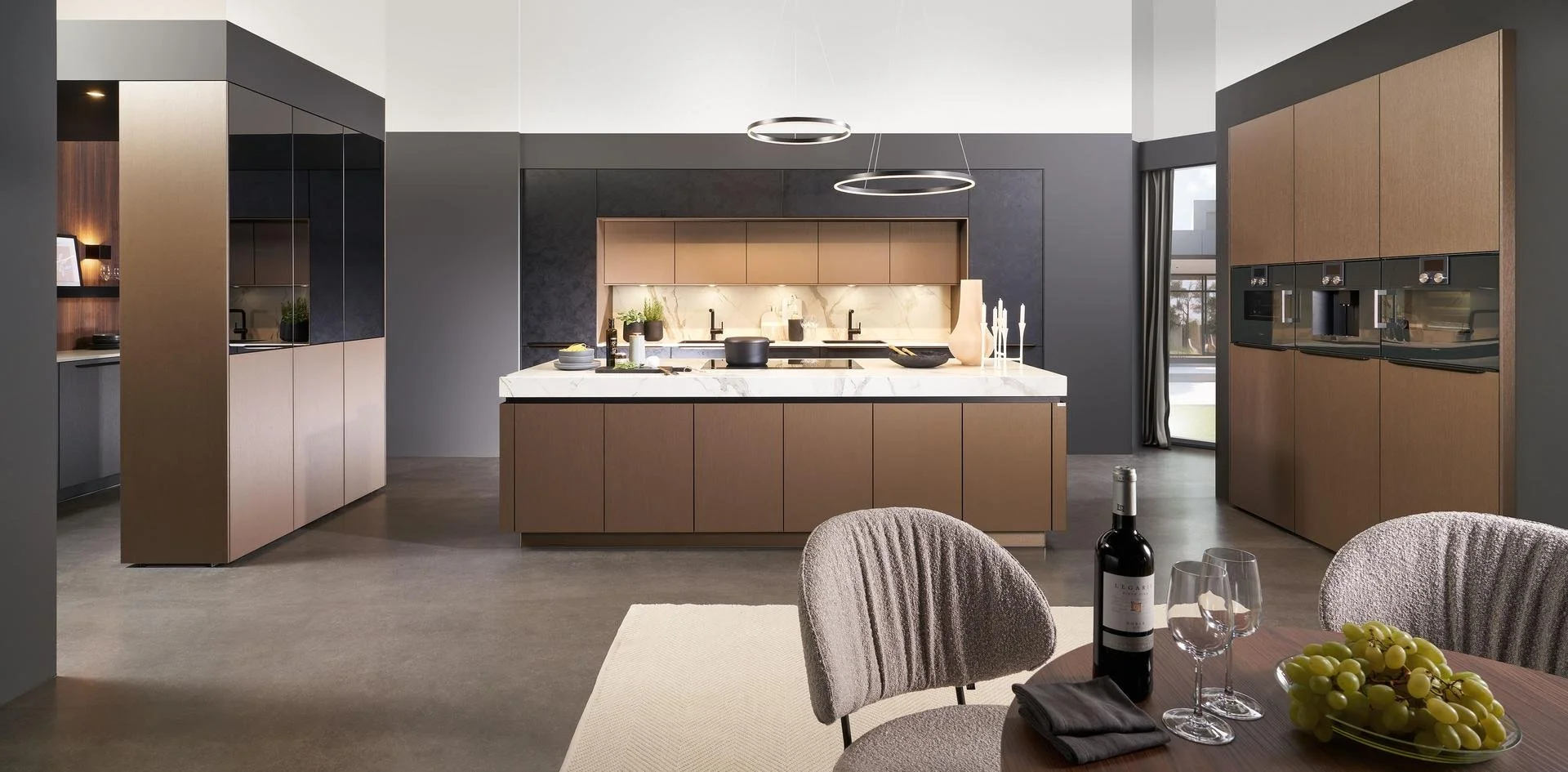 Cuisine moderne avec un plan de travail en marbre, armoires en bois clair et accents en noir, avec une table à manger en bois, des chaises en tissu gris, une bouteille de vin et des verres, décoration minimaliste et grande fenêtre