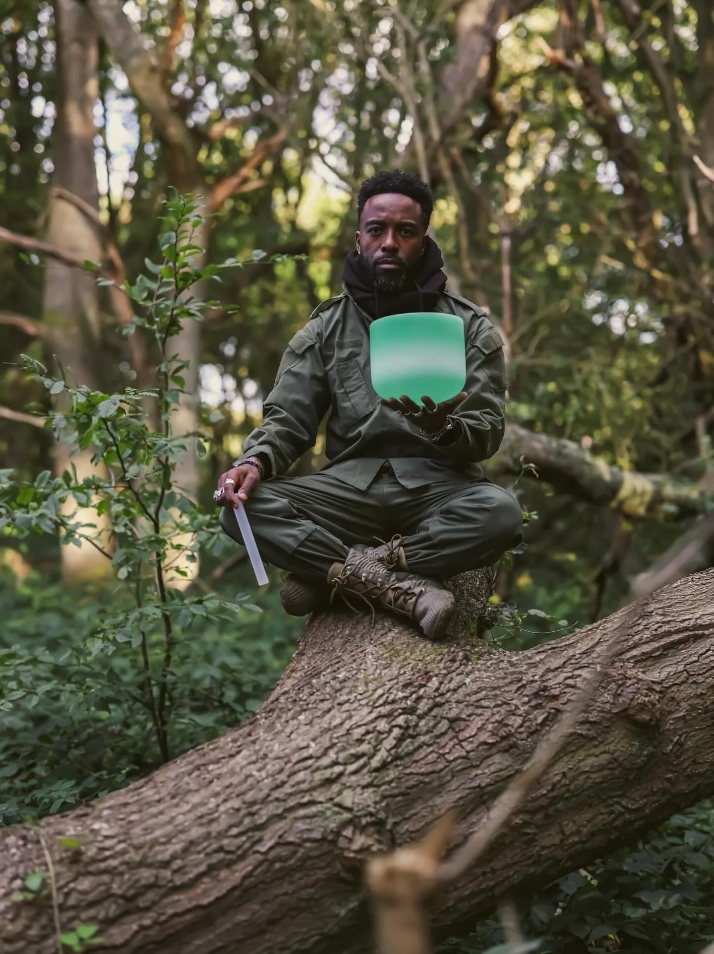 marcus joseph on a tree in the forest with green soundbowl in his hand