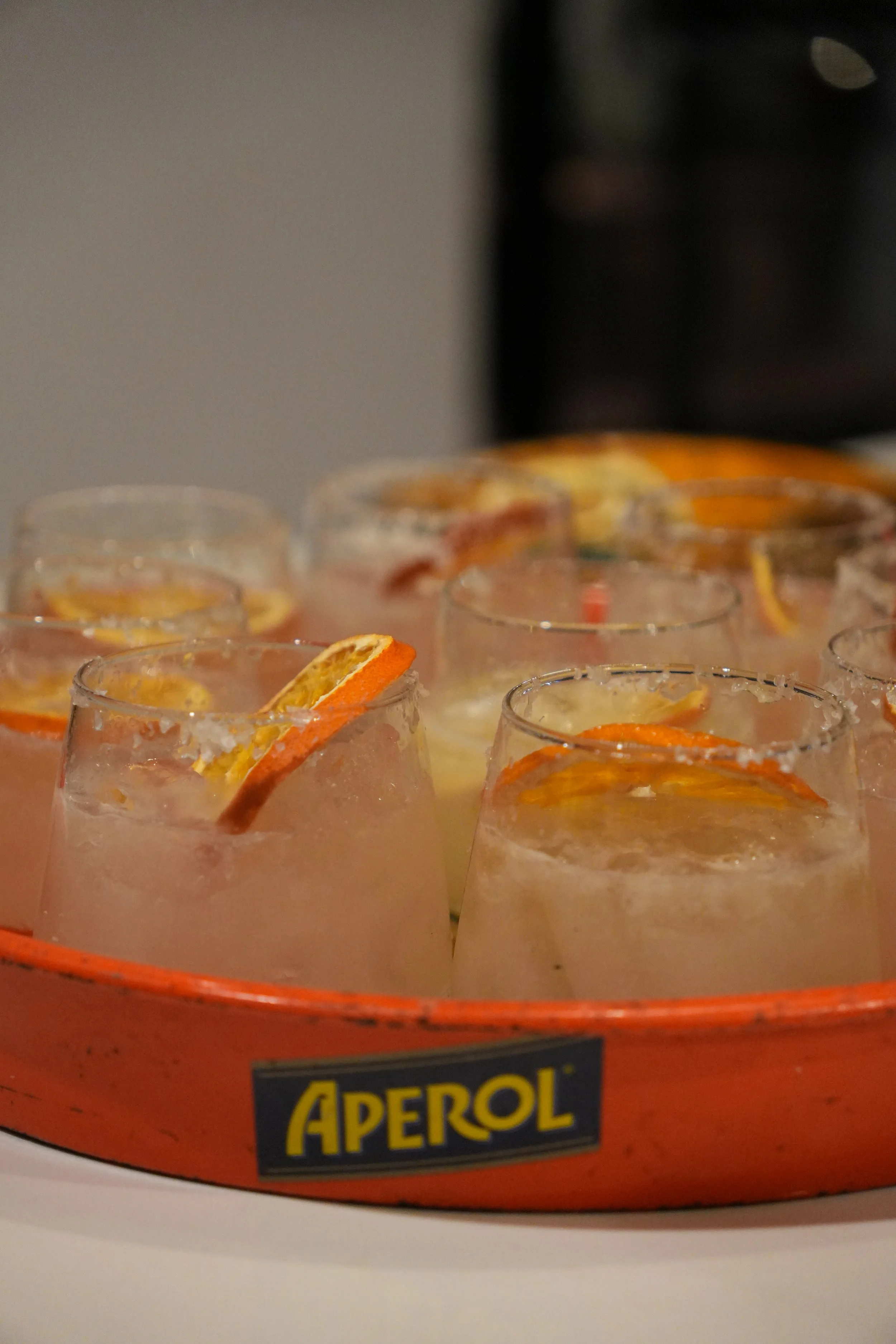 A tray of Aperol spritz cocktails garnished with orange slices.