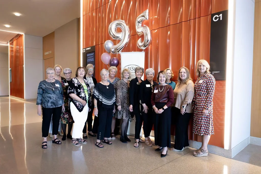 Group of women standing indoors, celebrating the Waukesha Service Club's 95th year of service.
