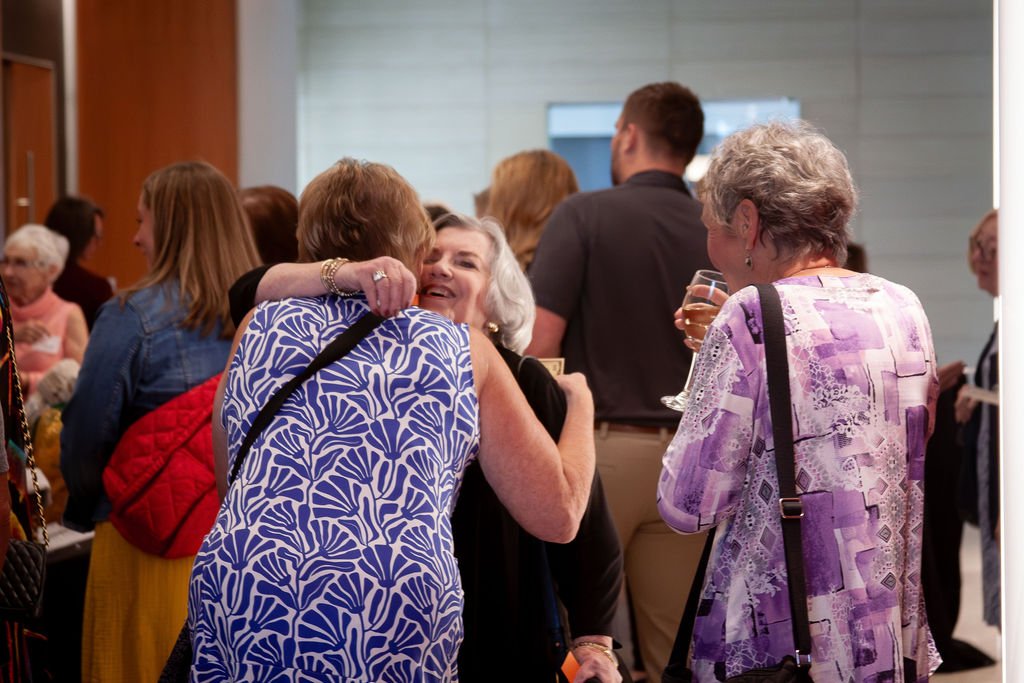 Waukesha Service Club members at a social gathering, including women hugging and smiling.