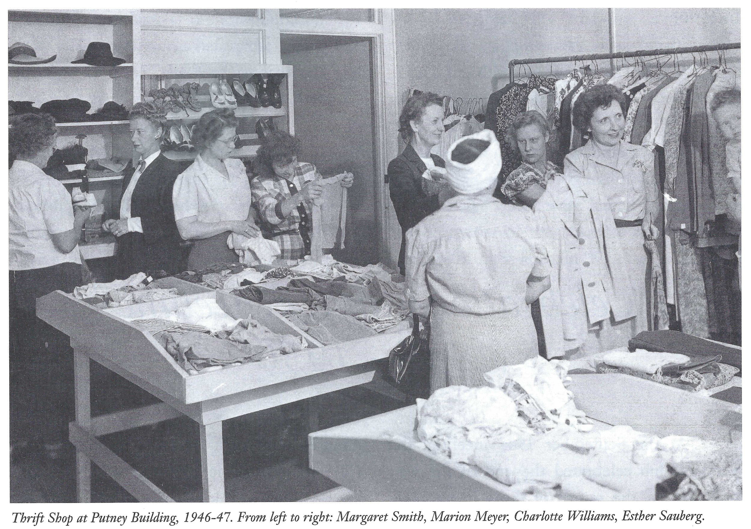 Black and white photo of people shopping at the Waukesha Service Club thrift shop in the 1940s with clothing racks and shelves of shoes, hats, and folded clothes.