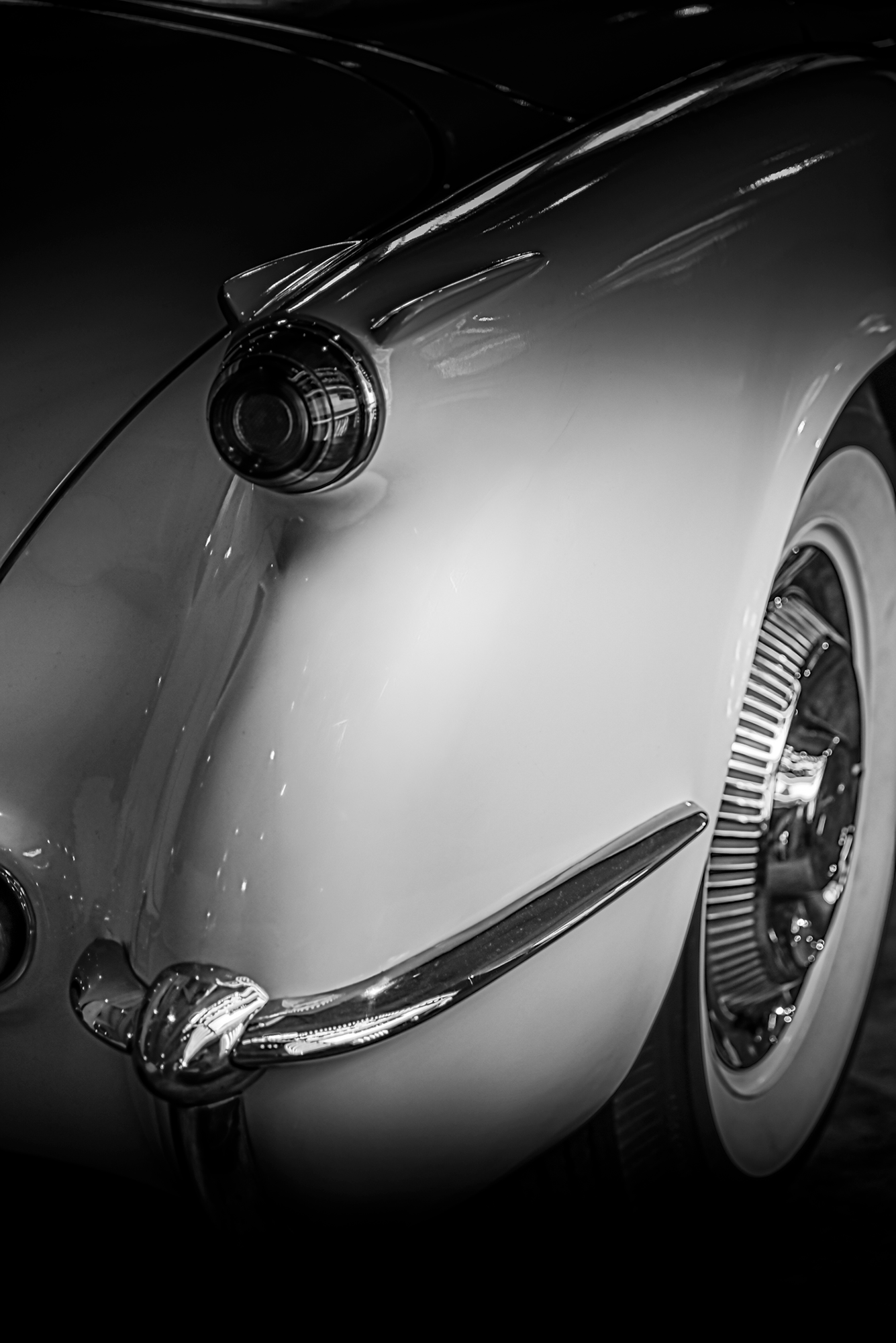Close-up of a classic vintage car, focusing on the front fender, headlight, and wheel.