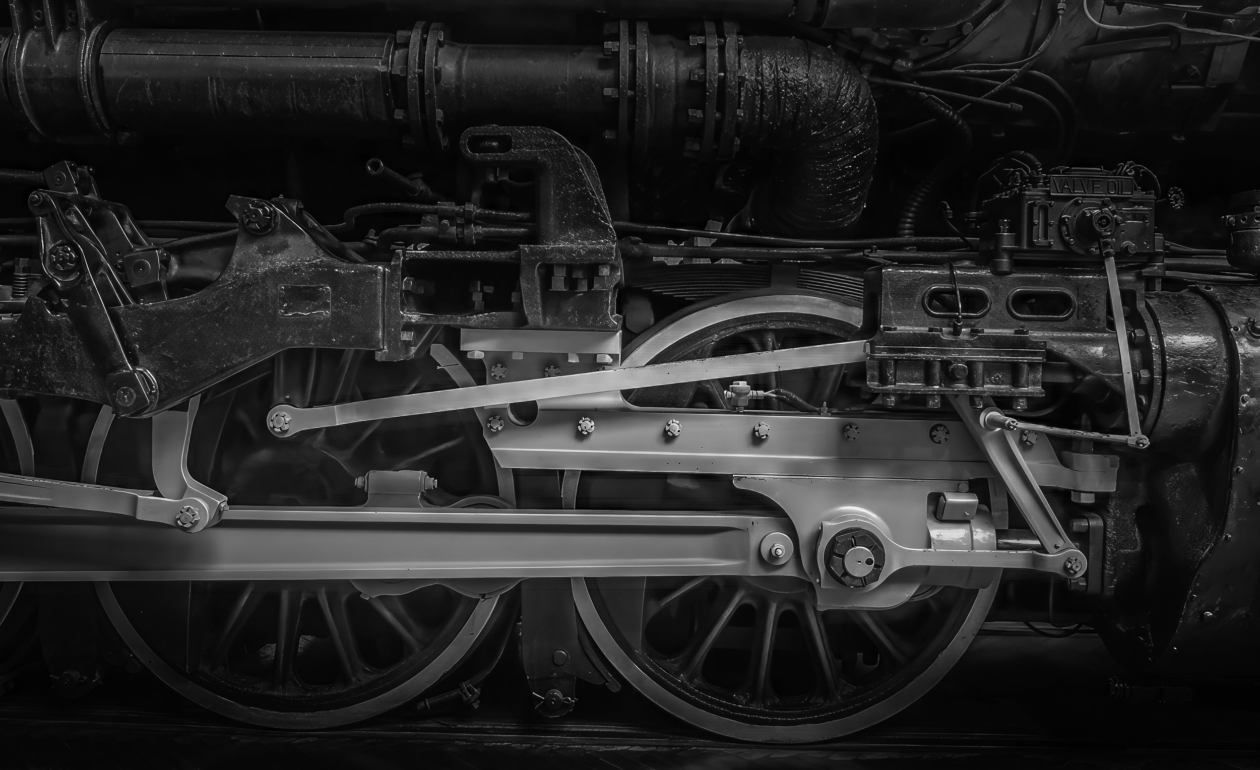 Black and white close-up of a vintage train wheel and mechanical components