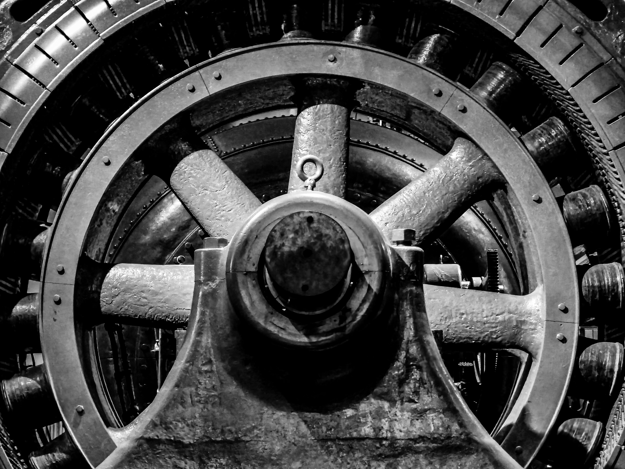 Close-up of the inner workings of a large mechanical gear system, black and white.