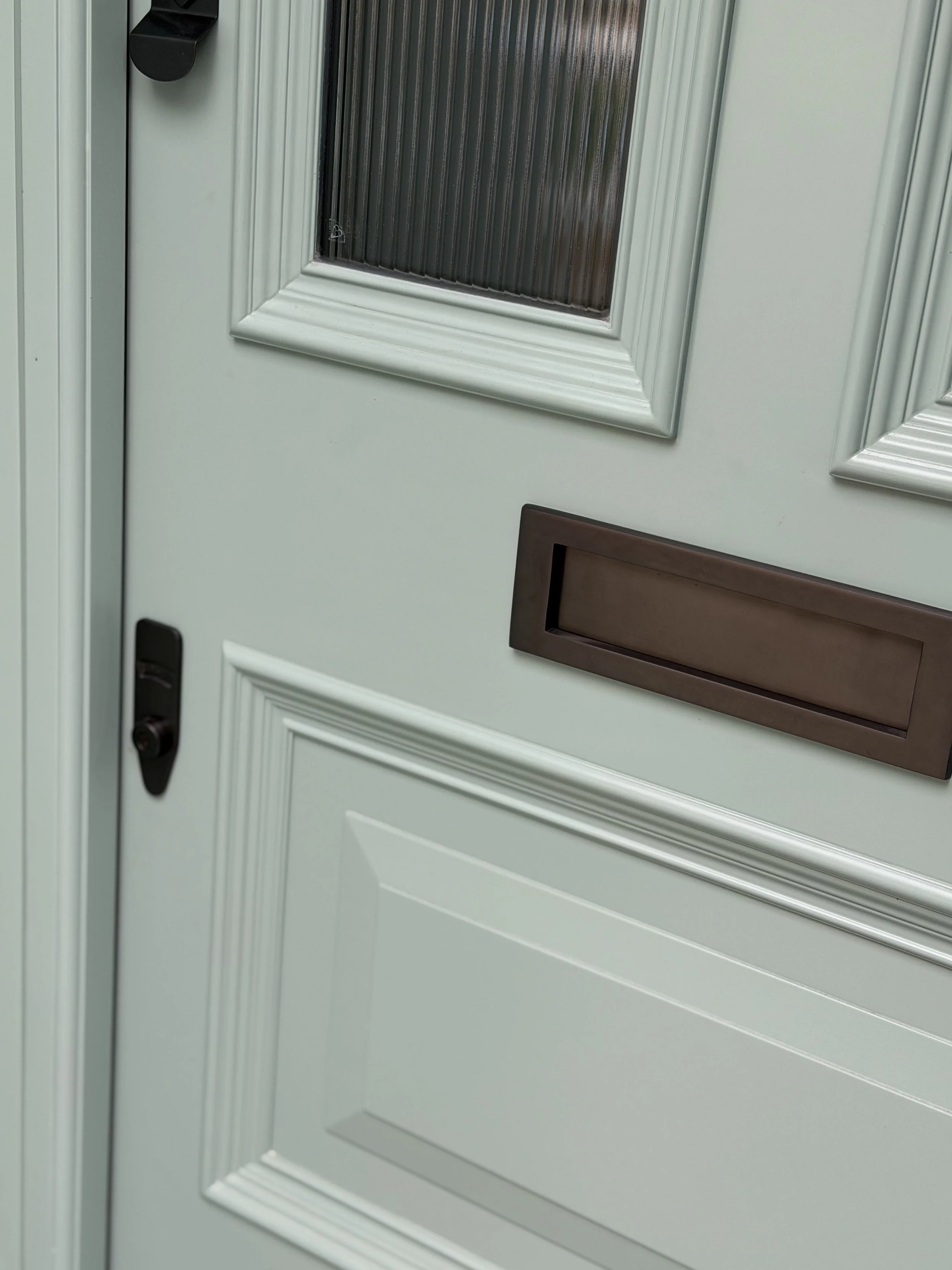 Banham locks in aged-bronze finish, a rich and moody tone that contrasts perfectly with the bright blue door.