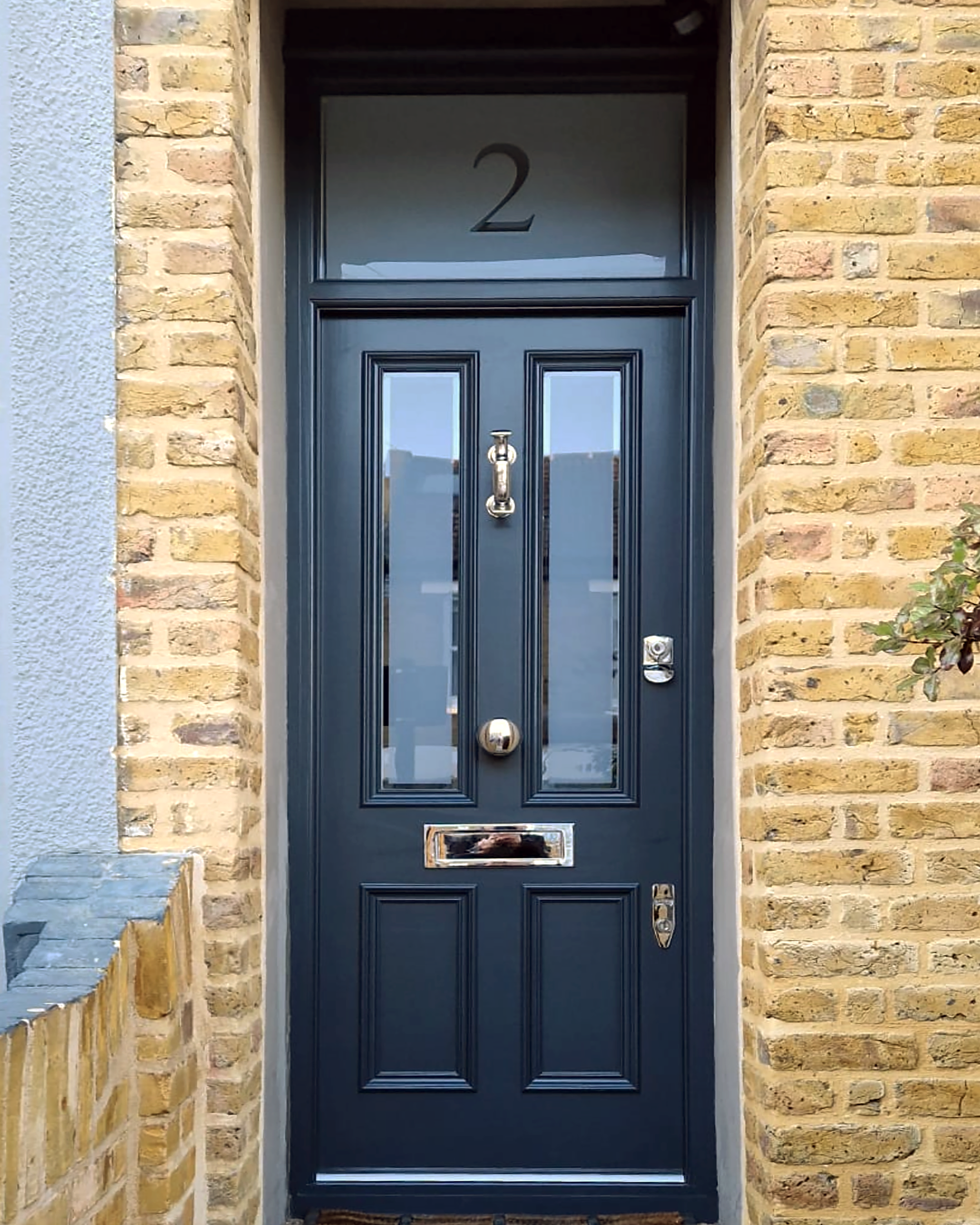After picture of a handmade bespoke accoya Front door painted dark blue with glass panels, a silver door knocker, a mail slot.