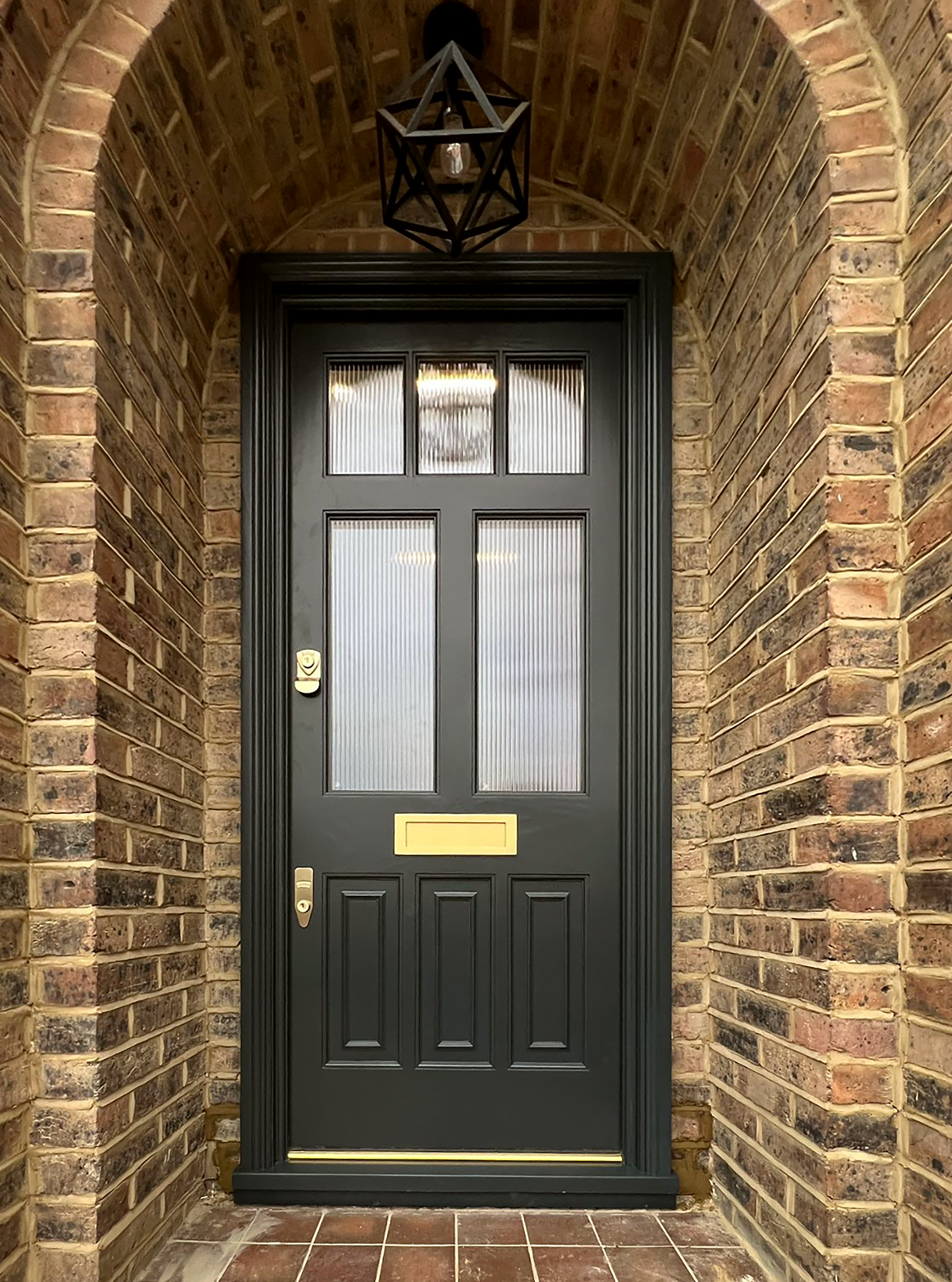 Black handmade bespoke accoya front door with decorative glass panels, offset gold mail slot and handle