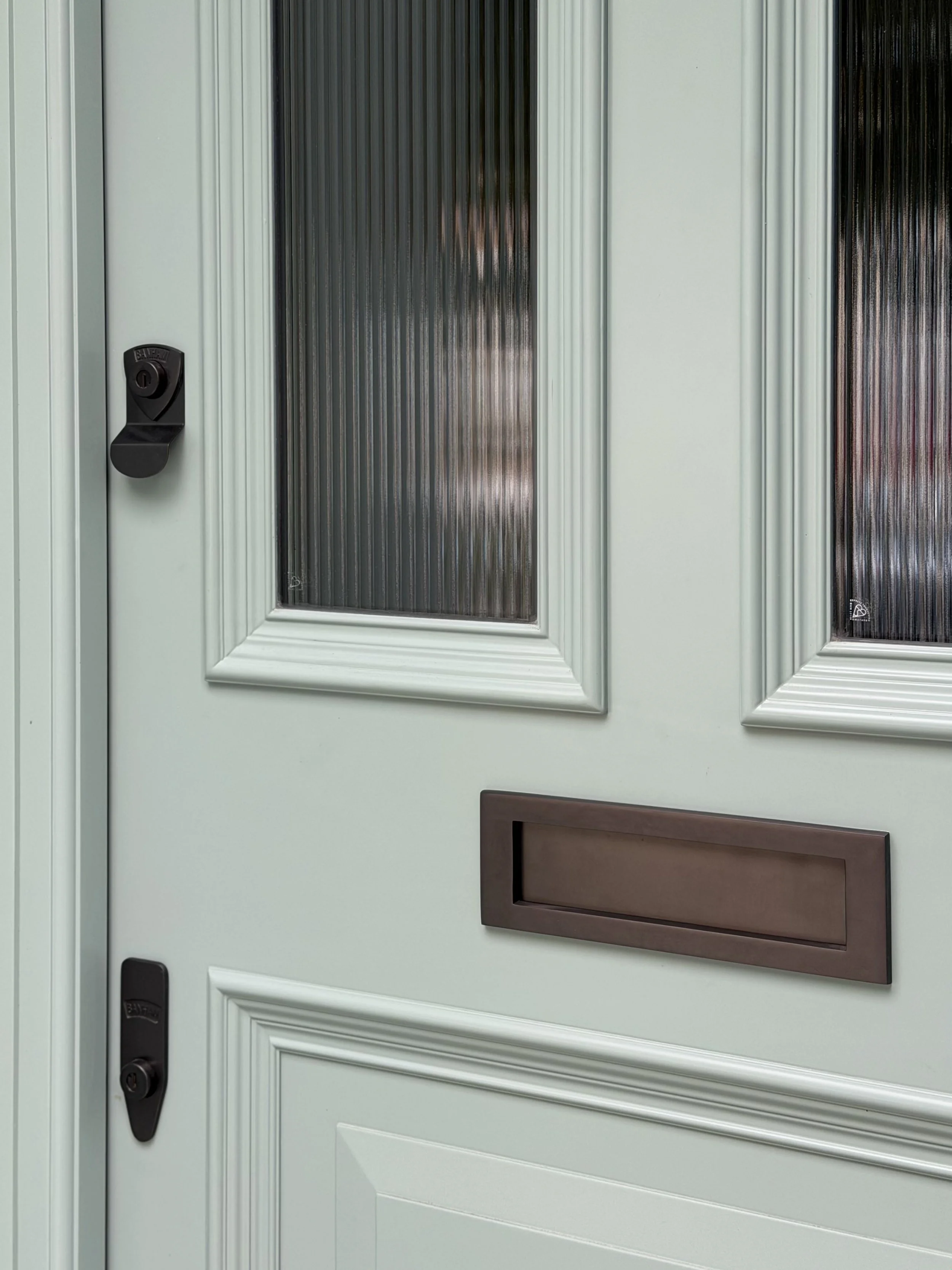 Precise vertical lines meet contrasting curves, with the frame echoing the profile of the door panel mouldings to create a cohesive and harmonious entrance.