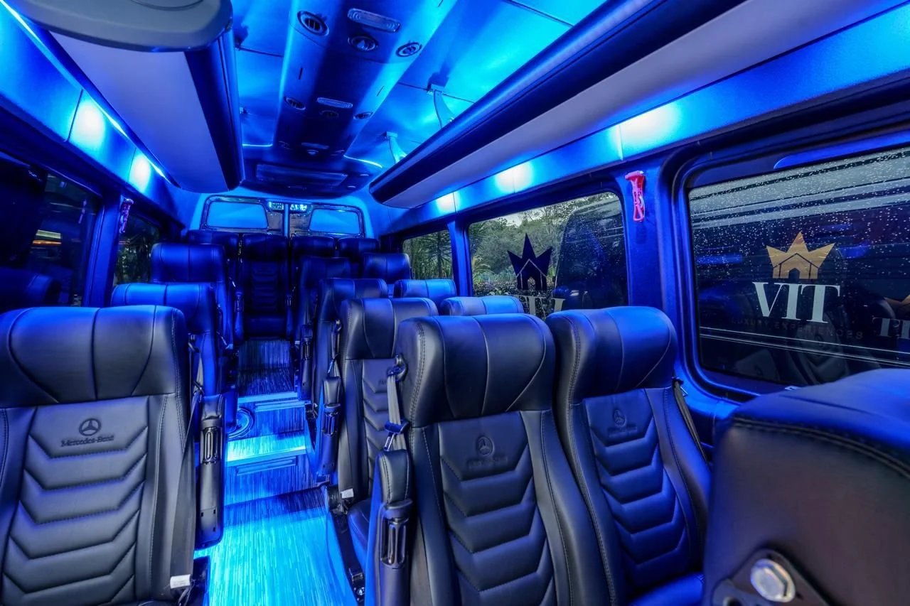 Inside a luxury bus with black leather seats and blue LED lighting, large windows showing rain outside, and the logo 'VIT' on the window.