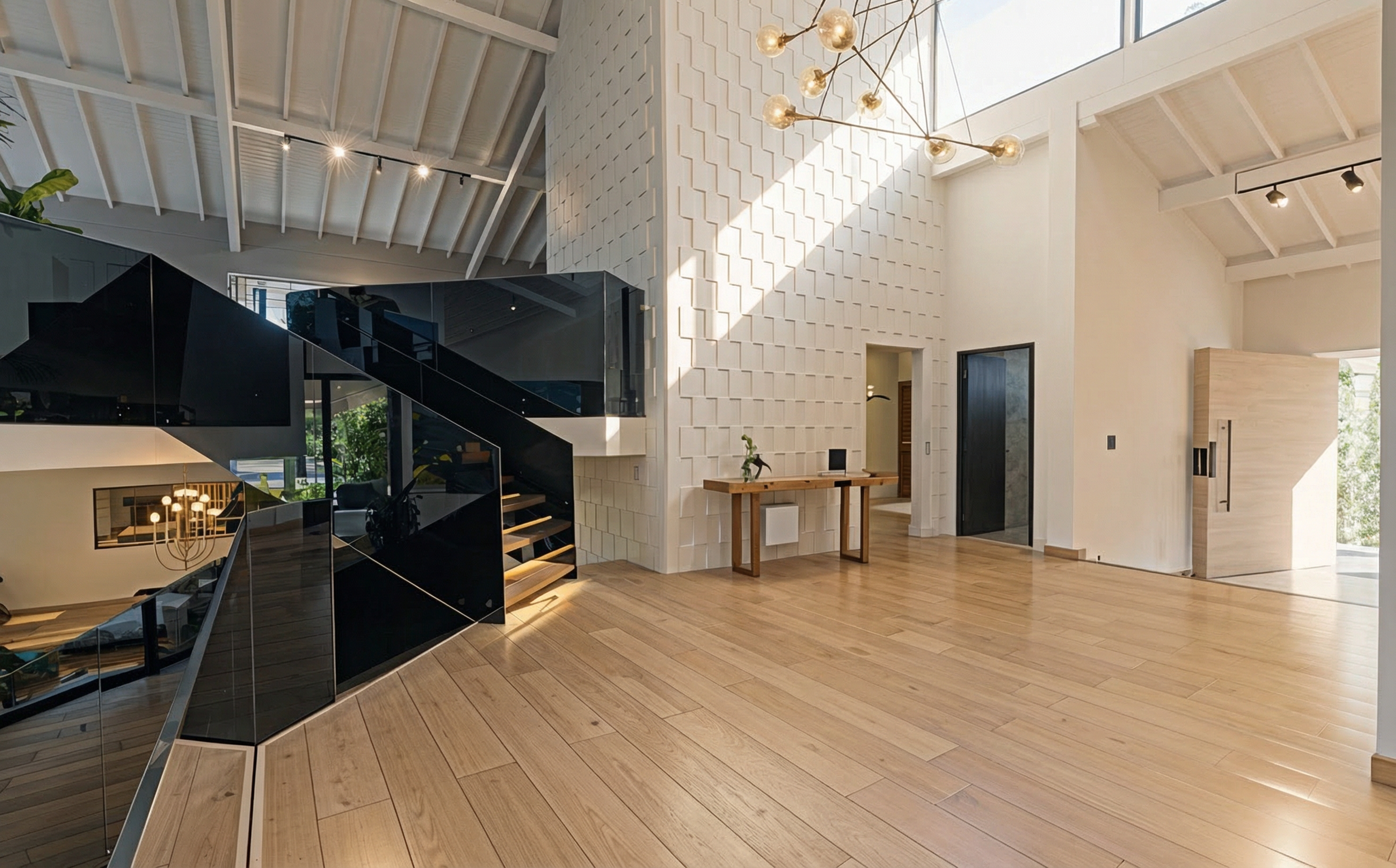 Modern high-ceiling living space with a skylight, white textured wall, wooden flooring, black staircase with glass railing, and minimalist decor.
