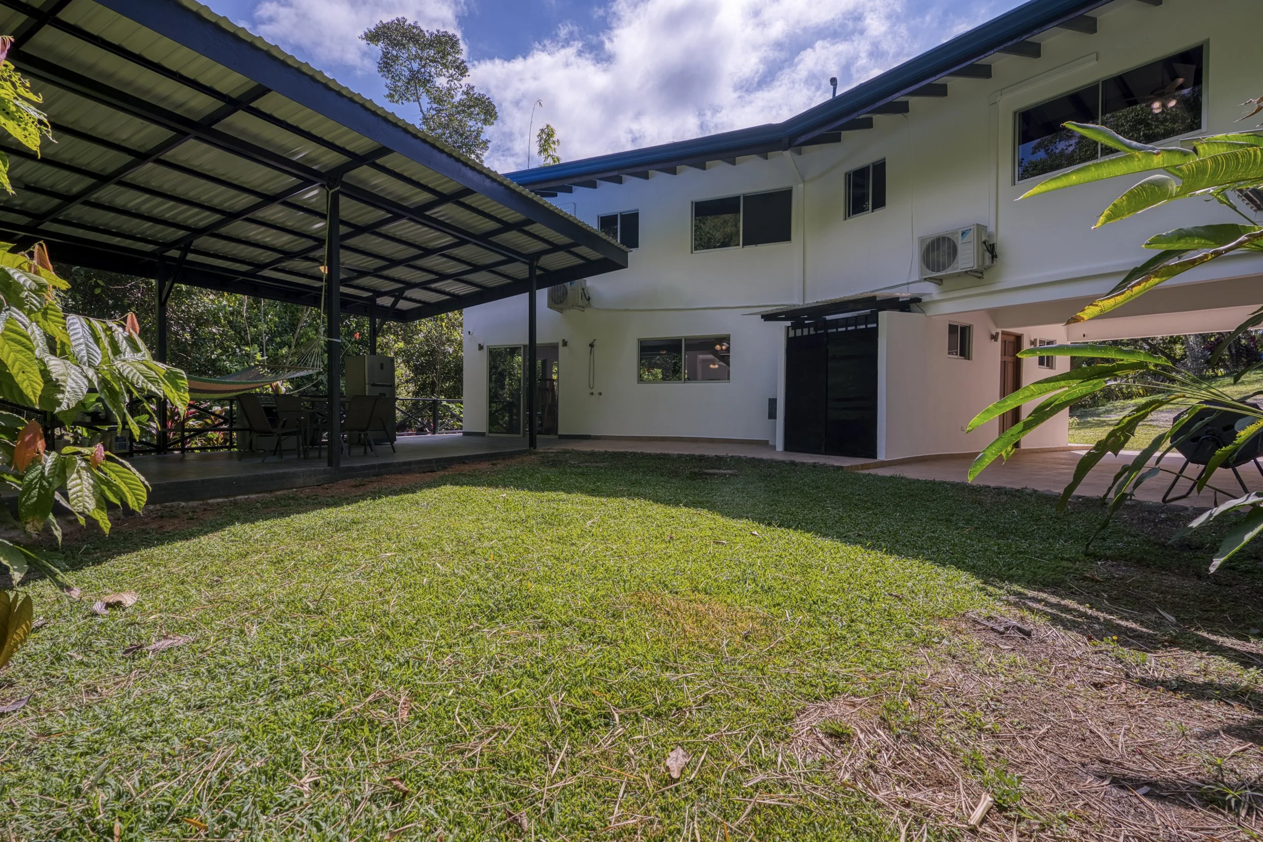 Alternate exterior perspective of Casa Arbol de Vida in its jungle setting. This is the rear of the home from the back yard. A well maintained septic system is cohesively integrated. There is a "jungle" shower here located just outside the sliding gl
