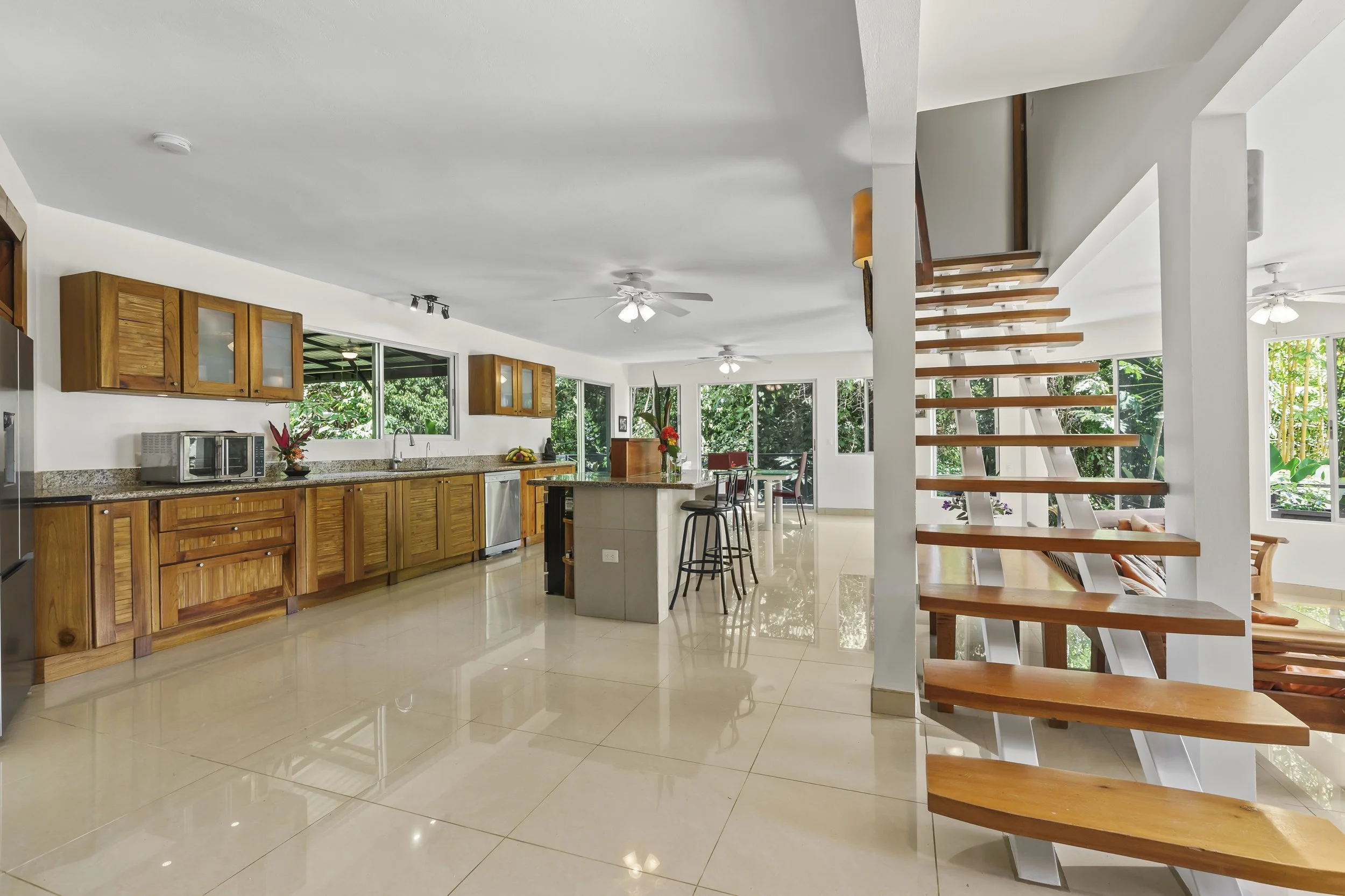 Bright open-concept kitchen and living space featuring a modern floating staircase design.
