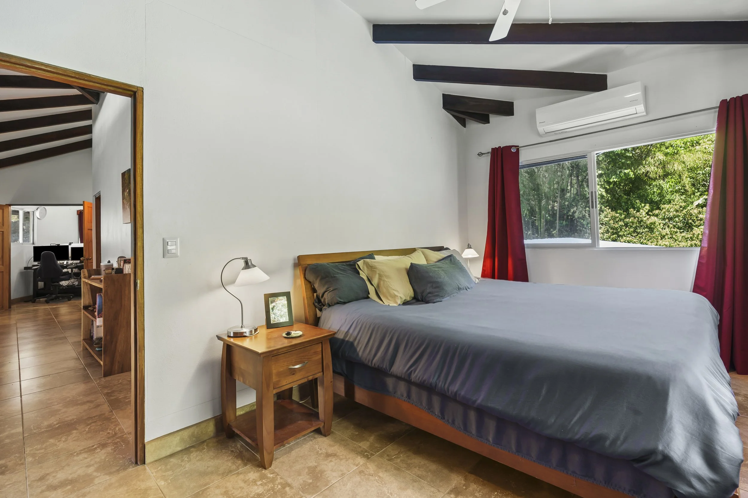 Guest bedroom with views of the surrounding jungle. For perspective, a king-sized bed is shown.