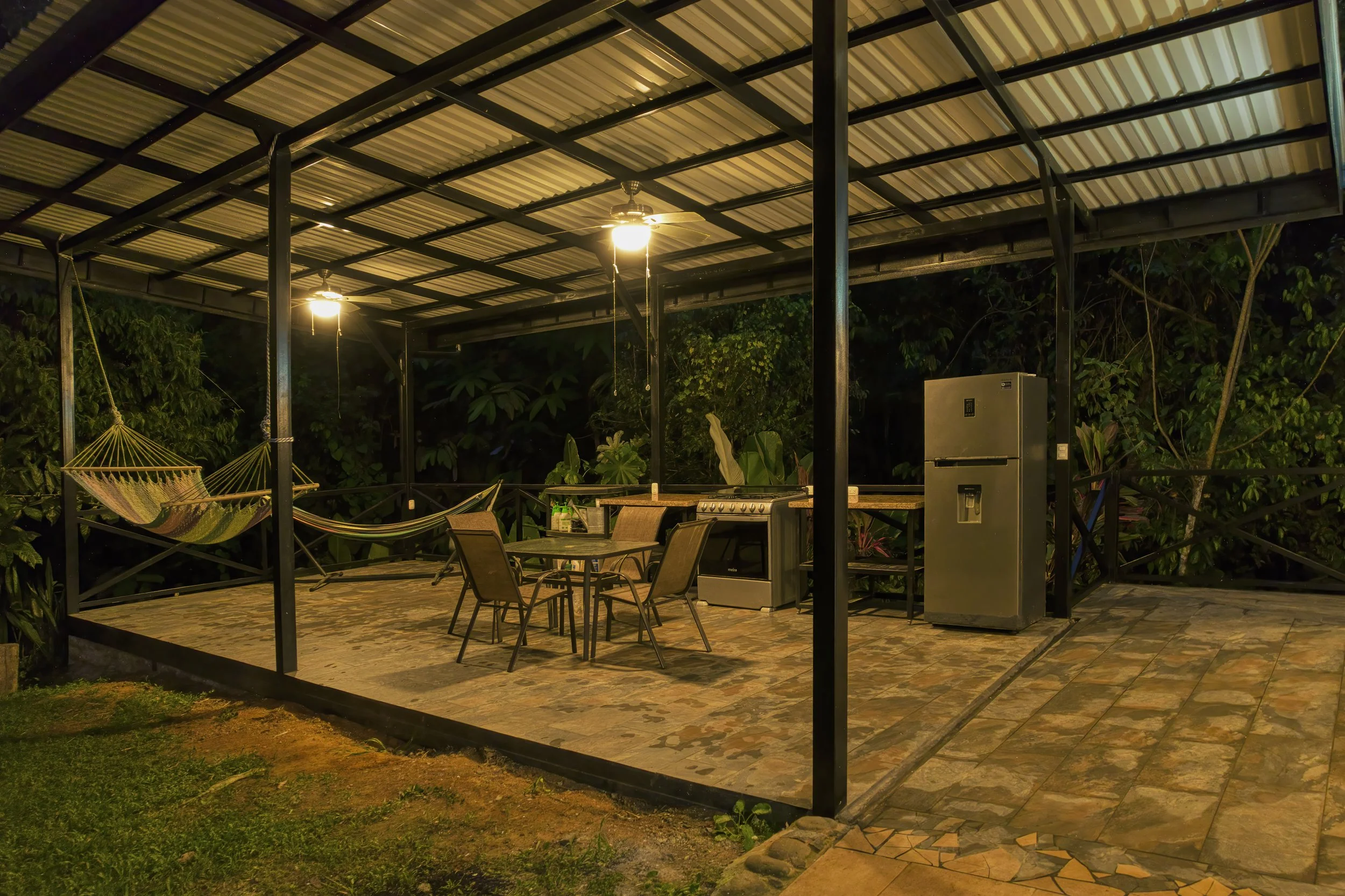 Rancho at night time. There is a second kitchen here (gas range / stove + refrigerator) and mobile counters with steel shelving; there are also plenty of power outlets. The overhead light fixtures with fans are exterior rated. This steel and concrete